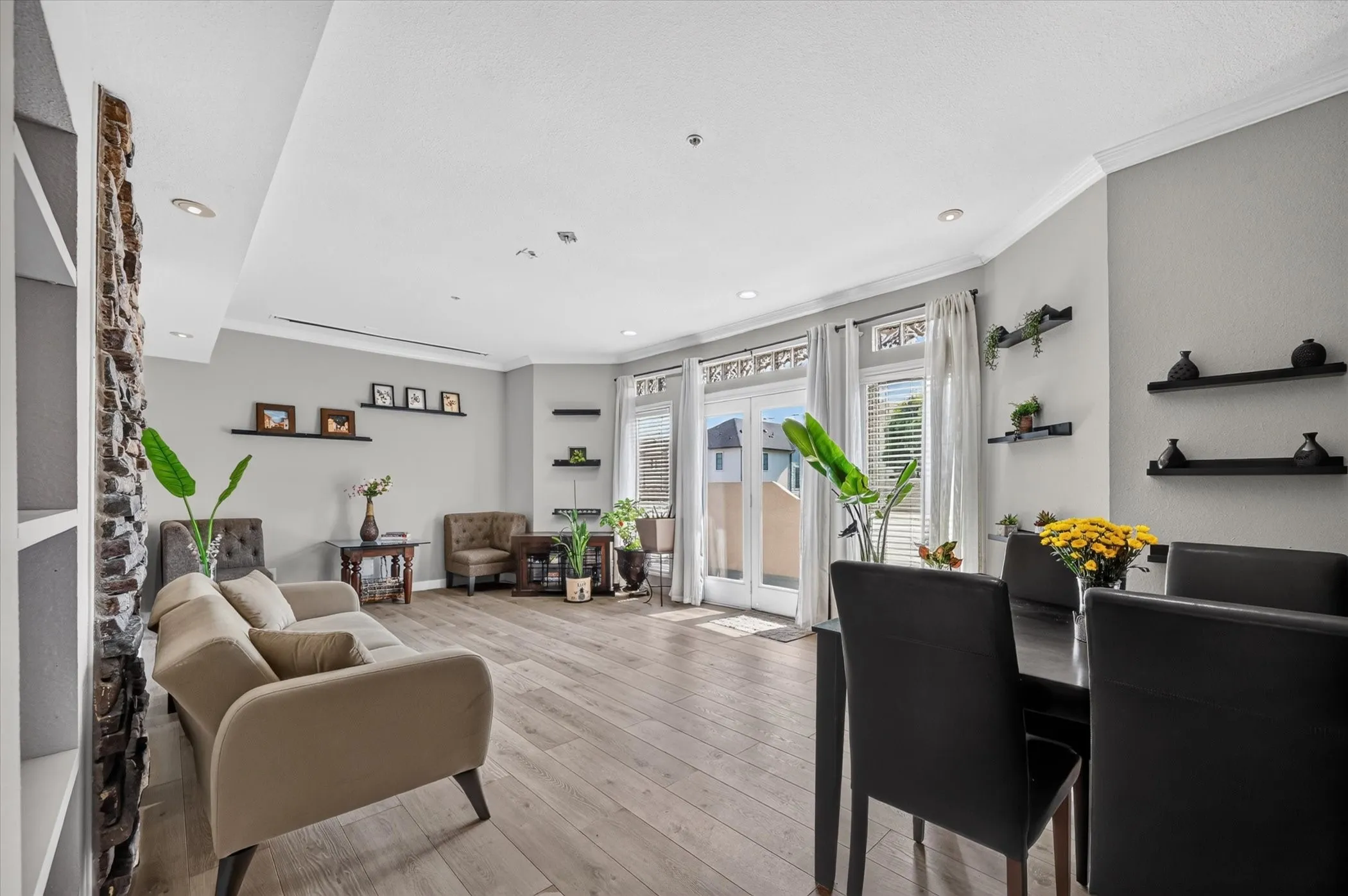 Recessed lighting illuminates the open living and dining areas featuring wood-finish flooring, crown molding, and double glass panel doors