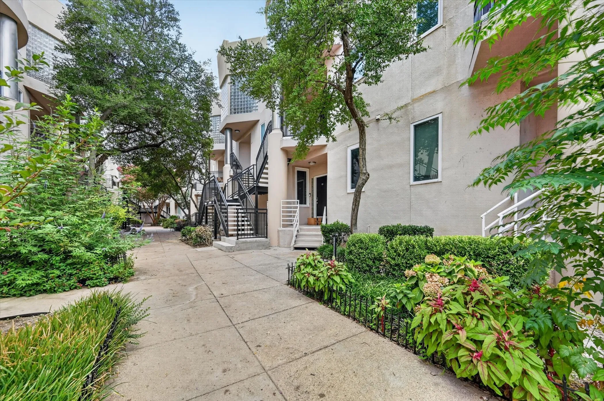 Stucco exterior with multiple levels, enhanced by mature trees and varied landscaping