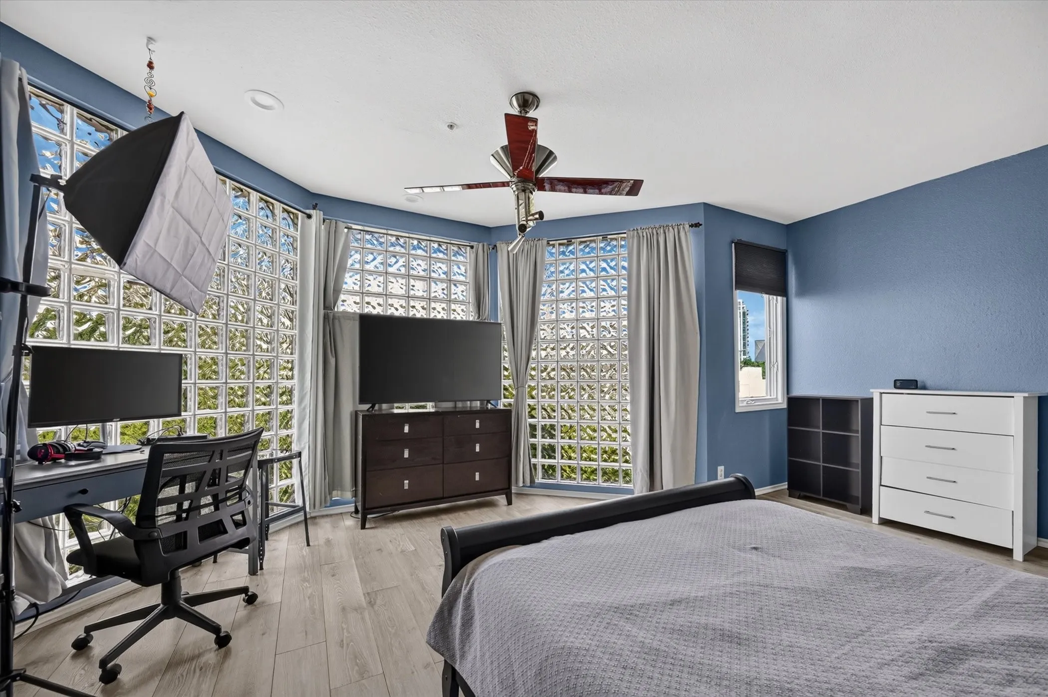 Curved wall of glass block windows, ceiling fan, recessed lighting, and wood-finish flooring