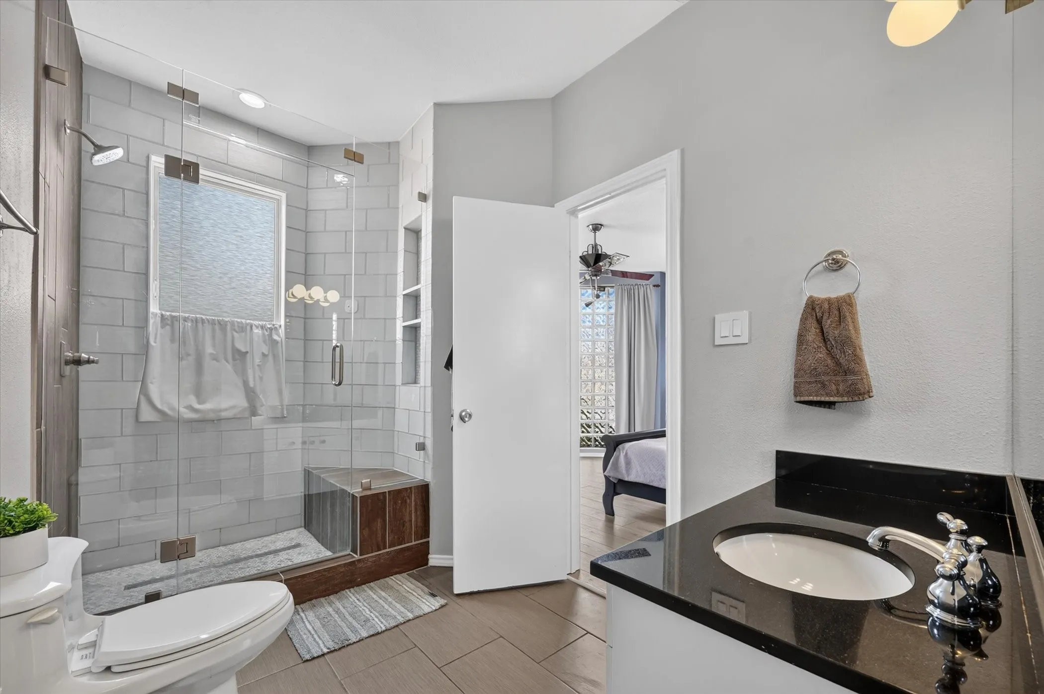 Glass-enclosed shower with subway tile surround, integrated shower bench, and a window