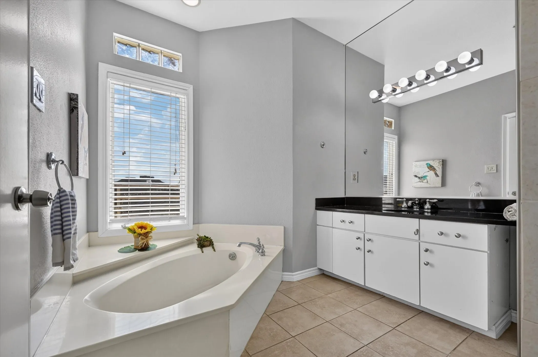 Soaking tub with a white surround and a window with blinds