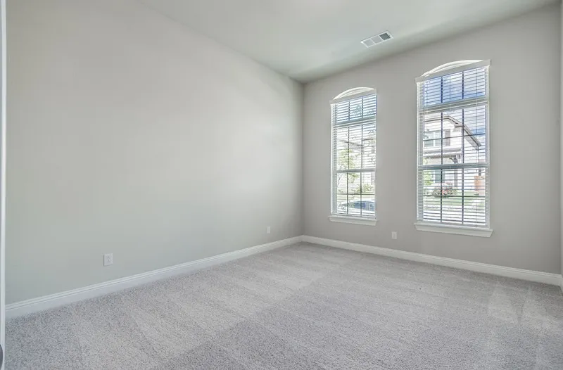 Arched windows with blinds, light gray wall paint, and gray textured carpeting