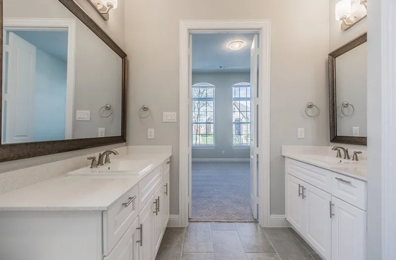 Dual vanities with white shaker cabinetry, light-toned countertops, and brushed nickel fixtures