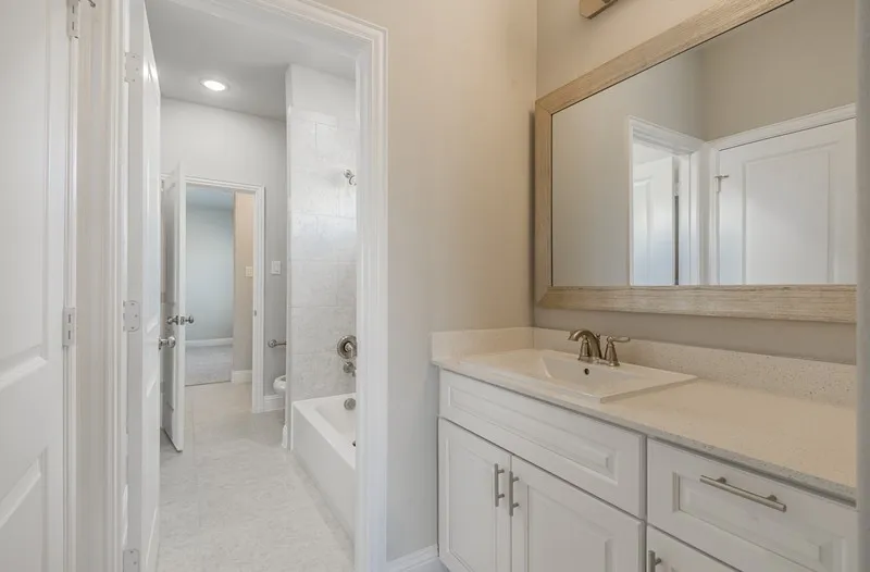 Bathroom featuring a white vanity with an undermount sink, light-toned countertop, and a framed mirror