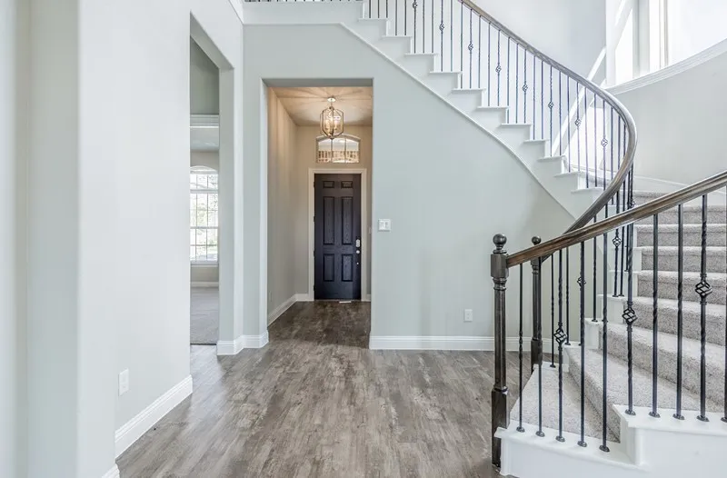 Curved staircase with iron balusters and wood handrails, wood-finish flooring, recessed lighting, and a chandelier