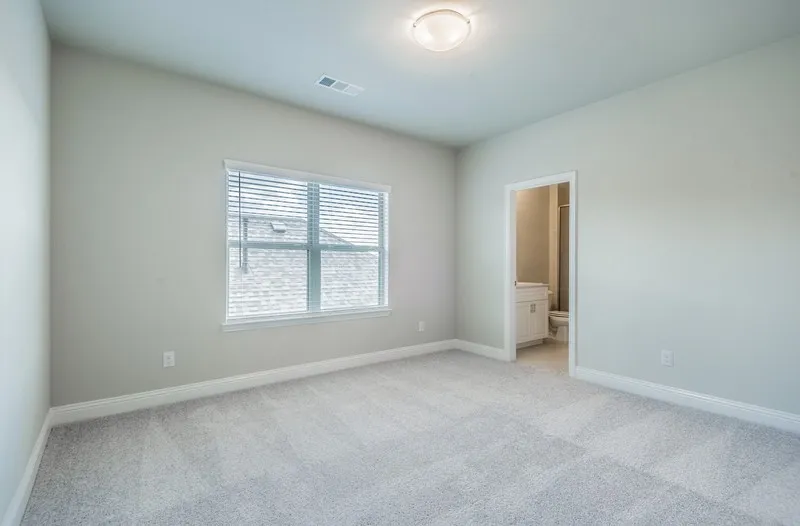 Spacious room featuring light gray carpet, neutral wall tones, a large window with blinds, and a flush-mount ceiling light