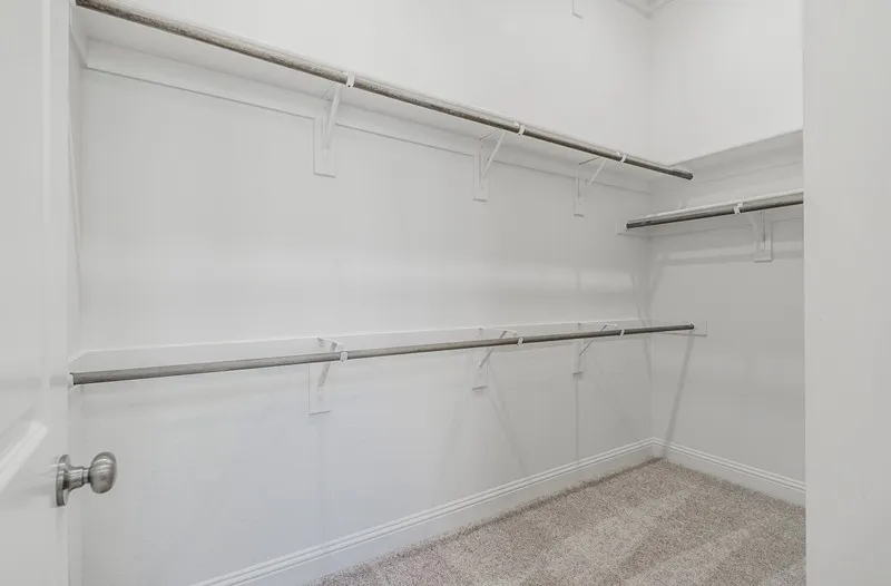 Walk-in closet featuring light-colored carpeting and multiple levels of shelving and hanging rods