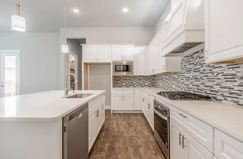Kitchen featuring white cabinetry, light-toned countertops, stainless steel appliances, a multi-tone tile backsplash, and wood-finish flooring