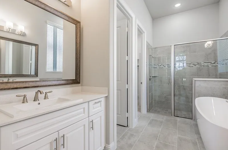 White vanity with a quartz countertop, framed mirror, and brushed nickel fixtures