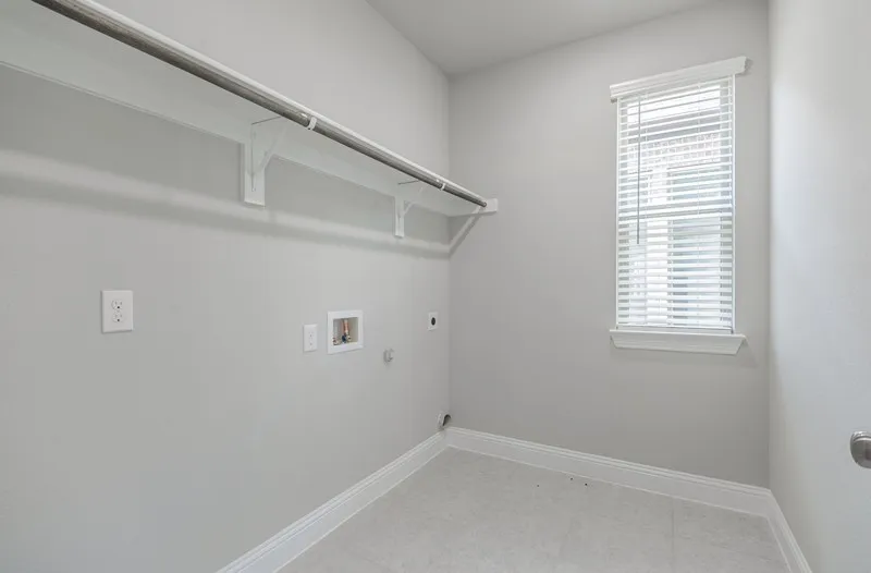 Laundry area featuring light gray wall paint, light-colored tile flooring, a window with horizontal blinds, and a built-in hanging rod with shelving