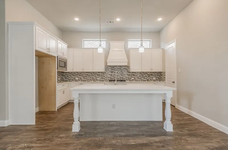 Kitchen featuring white cabinetry, a central island with turned legs, a tiled backsplash, recessed lighting, and pendant light fixtures