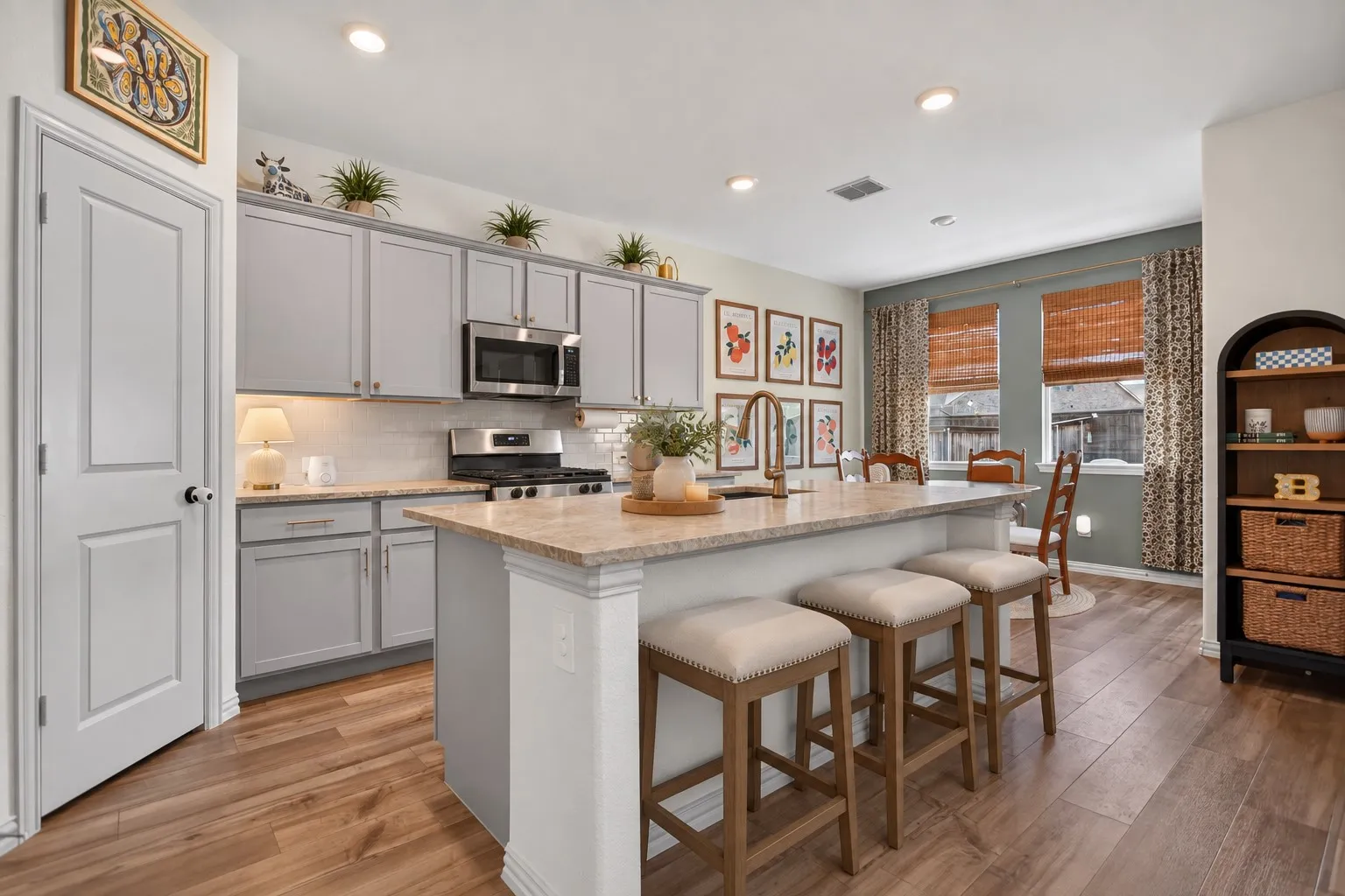 Kitchen featuring an island with counter seating, light-toned countertops, gray cabinetry, stainless steel appliances, and wood-finish flooring