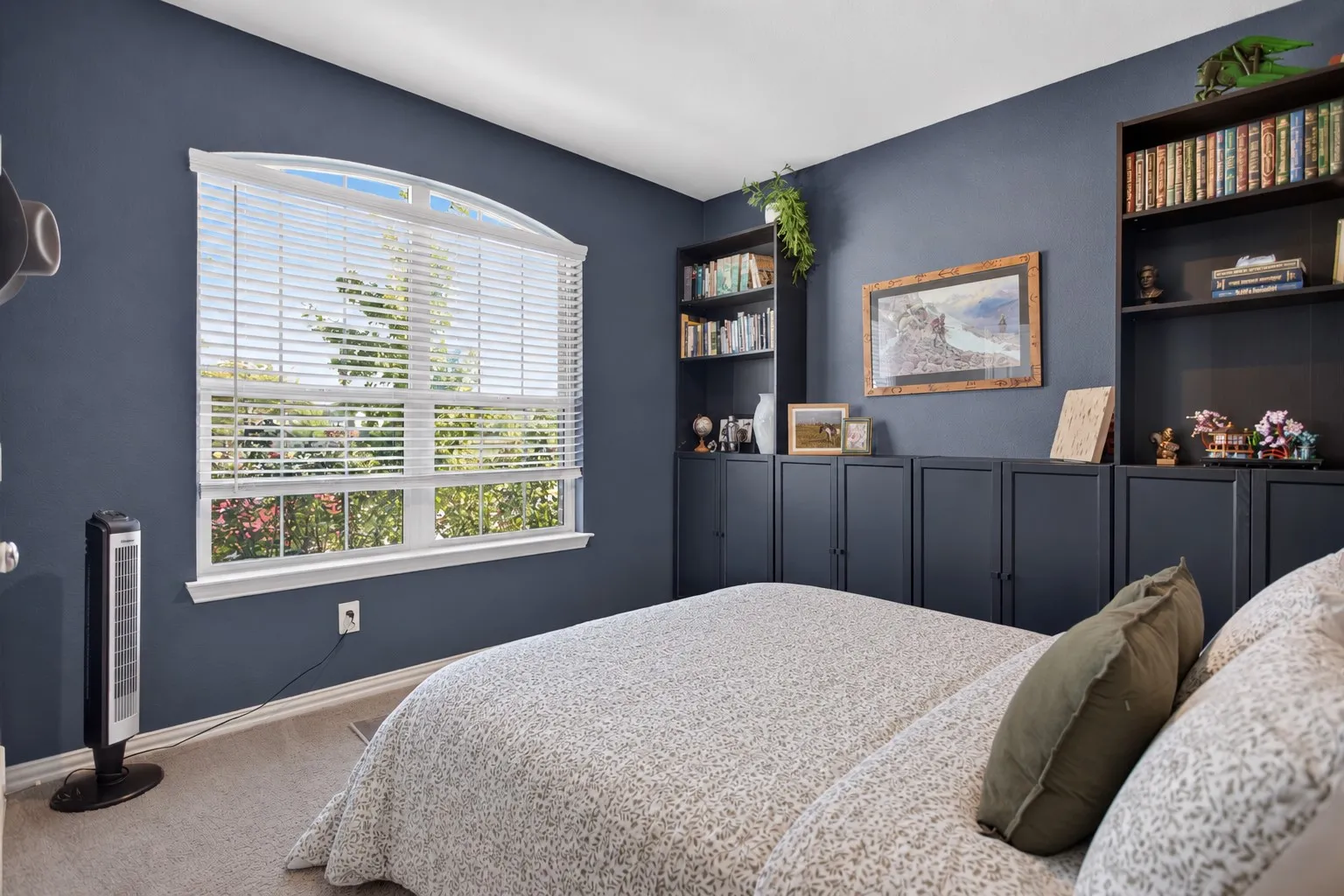 Arch-top window with blinds, expansive built-in cabinetry, and open shelving