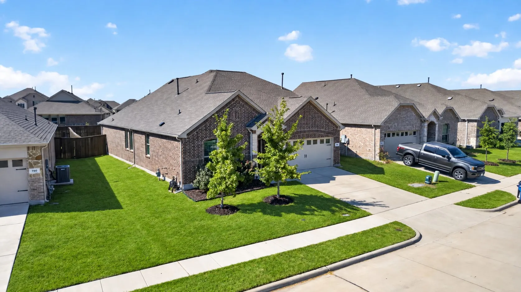 Brick exterior with stone accents, two-car garage, concrete driveway, and front landscaping