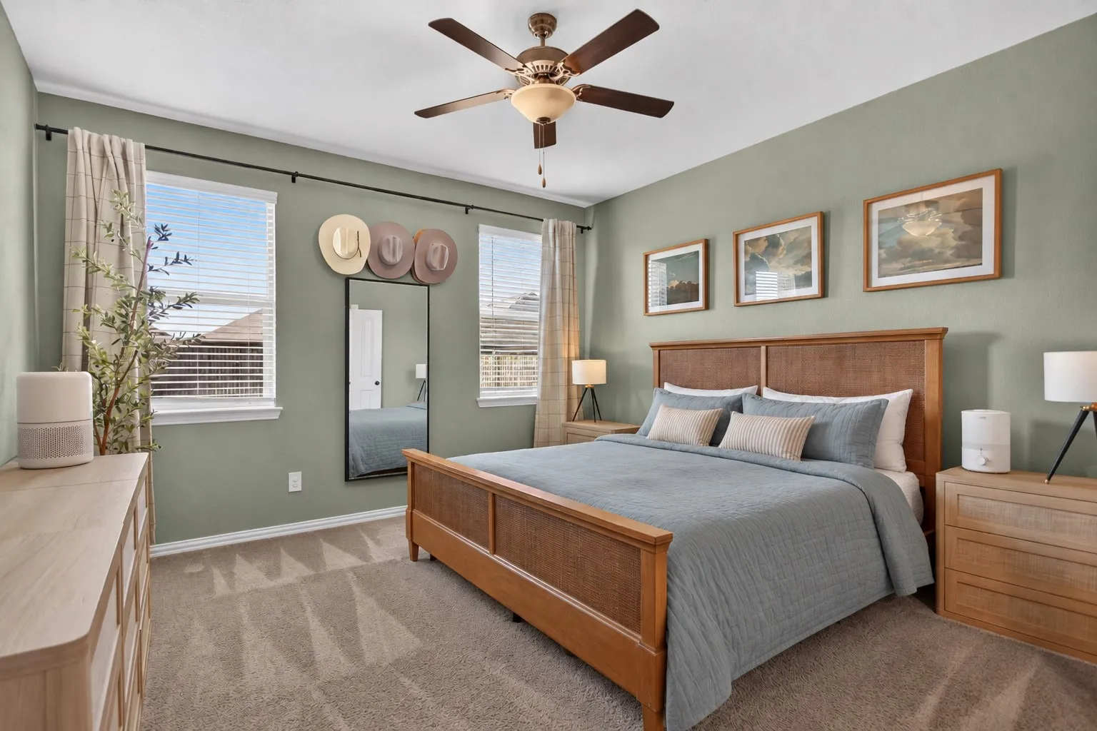 Wall-to-wall carpeting, dual windows with blinds, ceiling fan with integrated lighting, recessed wall-mounted mirror, and a wood-finish bed frame