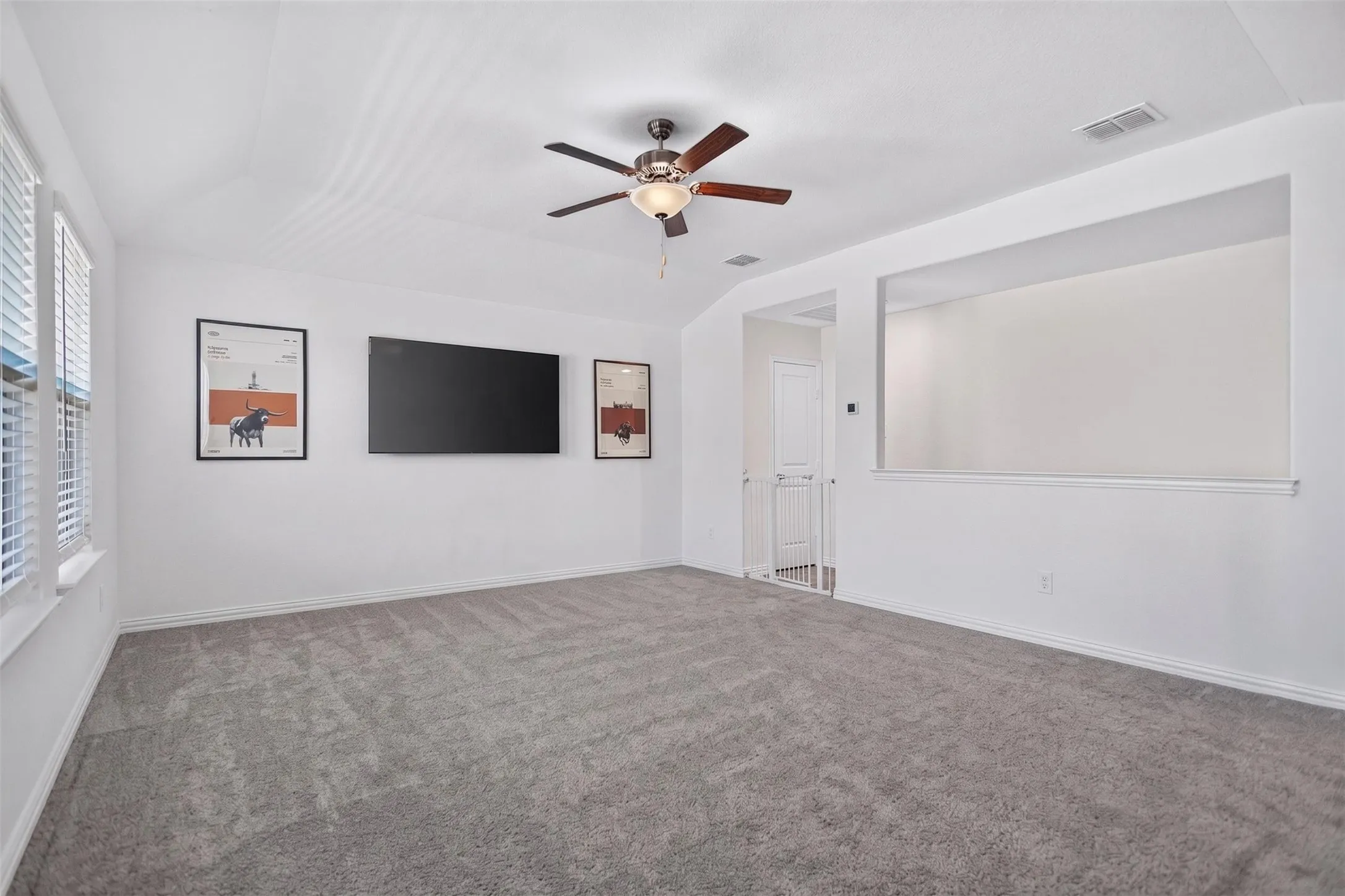 Spacious room with sloped ceiling, light gray carpet, and a ceiling fan with integrated lighting