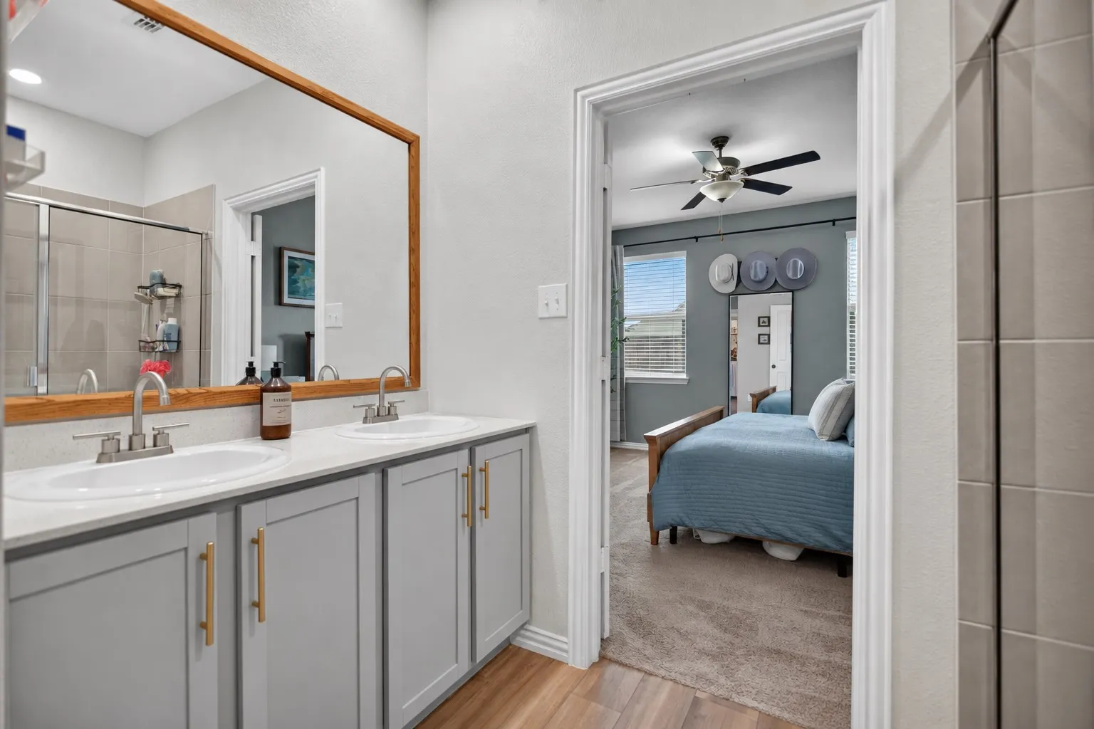 Dual vanity with undermount sinks, light gray cabinetry, and gold-finish hardware