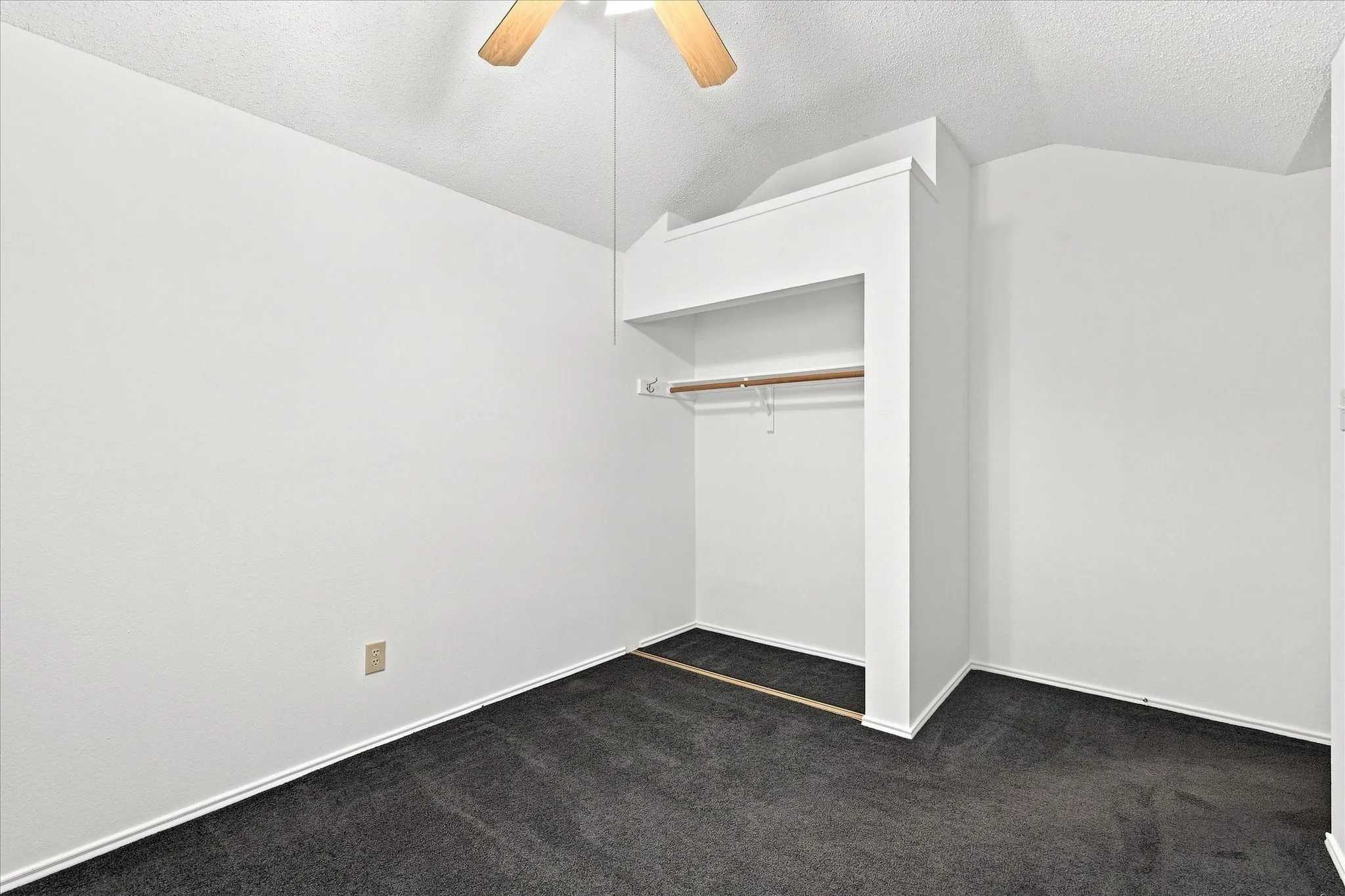 Bedroom #2 w/vaulted ceiling, a ceiling fan, recessed alcove with an integrated closet rod, and dark carpeting