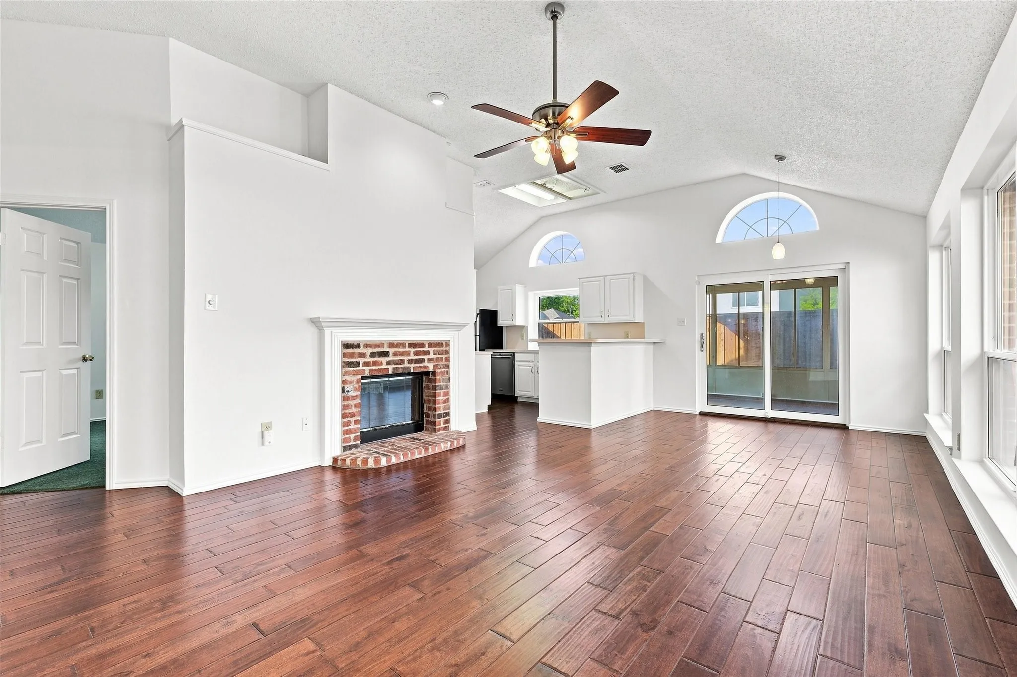 Living Room and Dining Room with engineered hardwood flooring, brick fireplace with mantel, white cabinetry, and sliding glass door