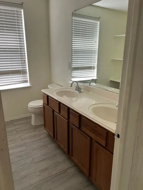Dual vanity with integrated sinks, wood-finish cabinetry, and a full-width mirror