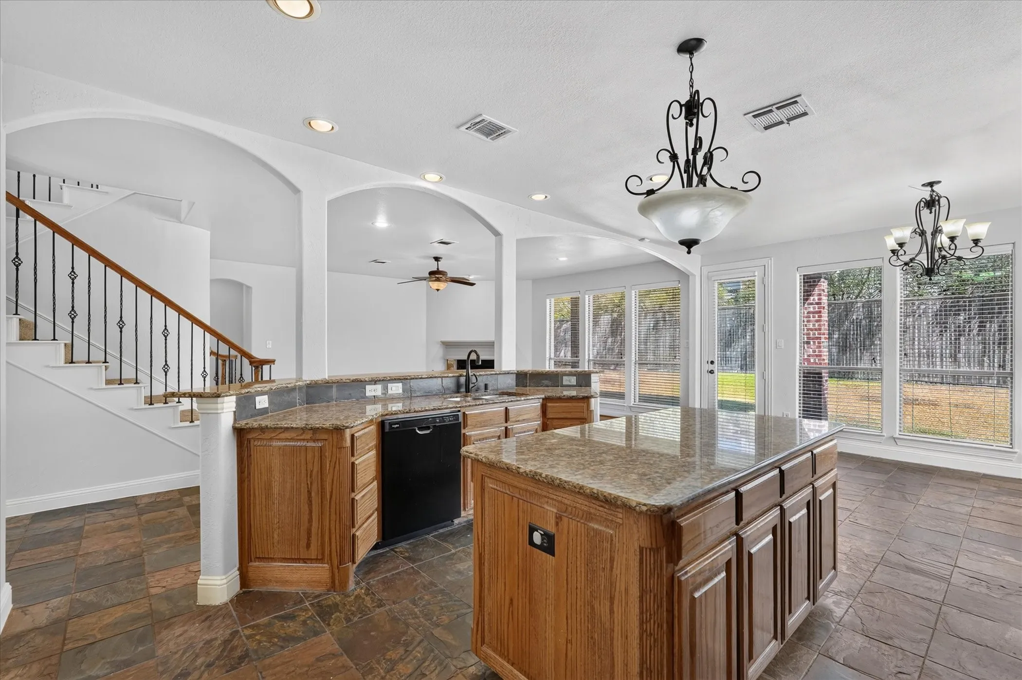 Kitchen featuring wood cabinetry, stone countertops, a central island, and tile flooring