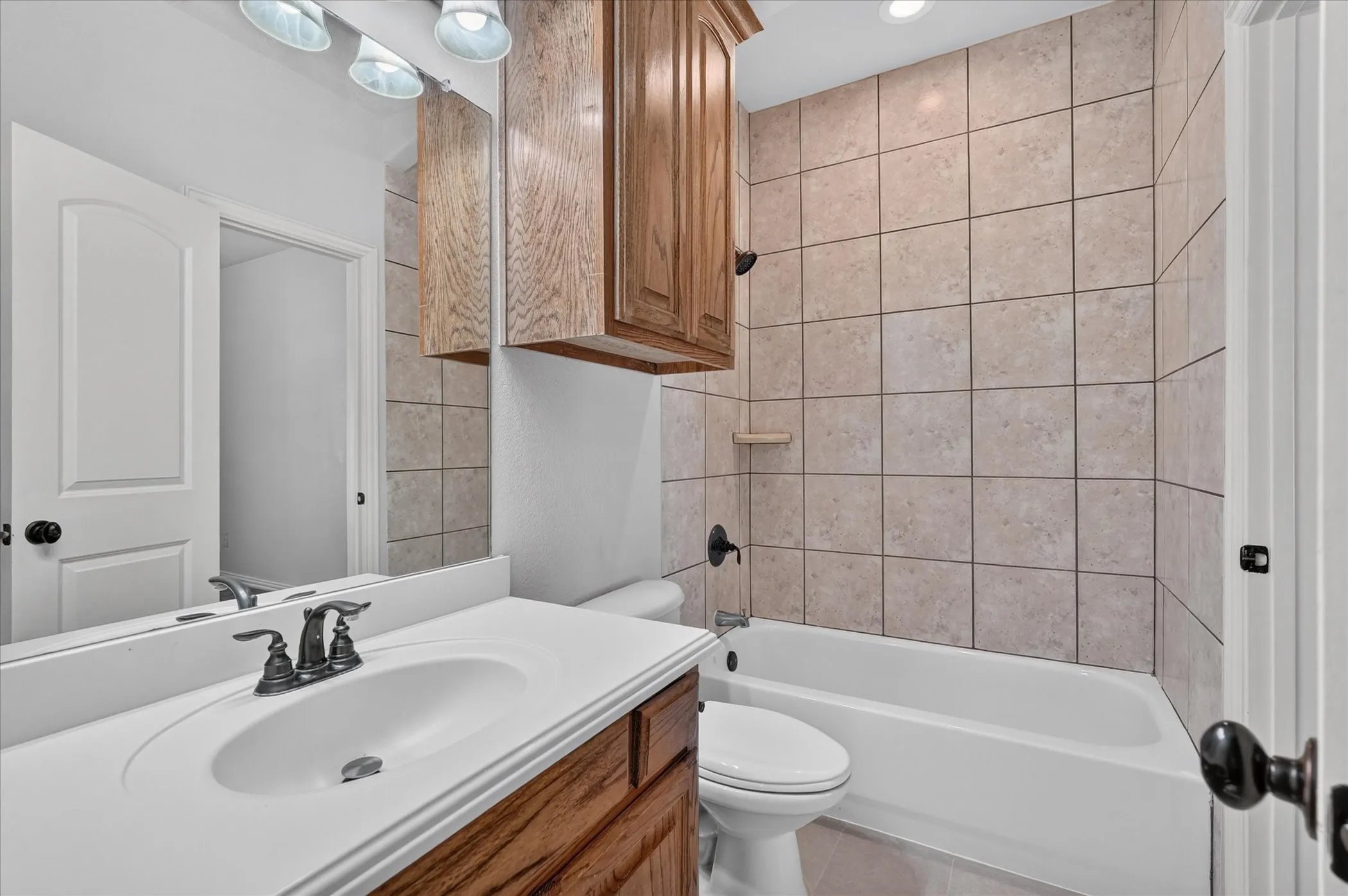 Bathroom featuring a vanity with an integrated sink, wood-finish cabinetry, a mirror, and a tiled shower-tub combination