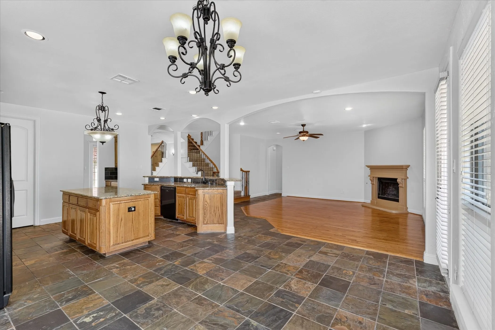 Open-concept living space featuring a fireplace with a mantel, wood-finish flooring, and slate tile flooring