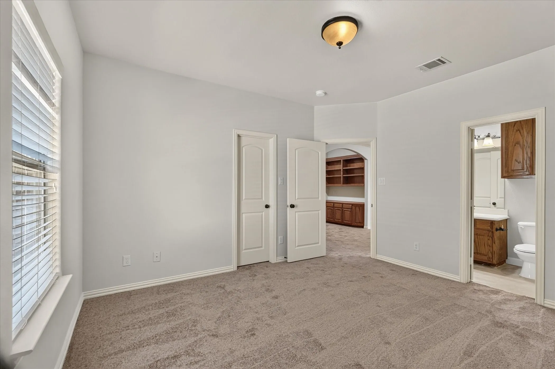 Carpeted interior space with light gray walls, a window with horizontal blinds, and a semi-flush mount ceiling fixture