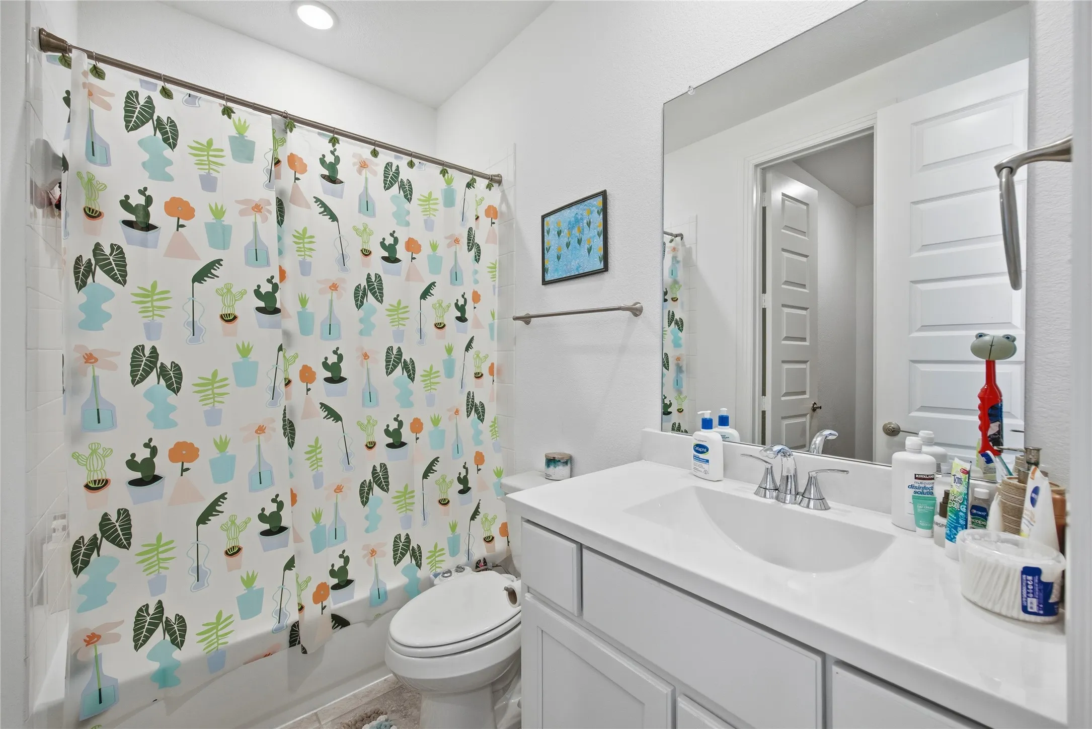 White vanity with integrated sink, chrome faucet, and expansive mirror