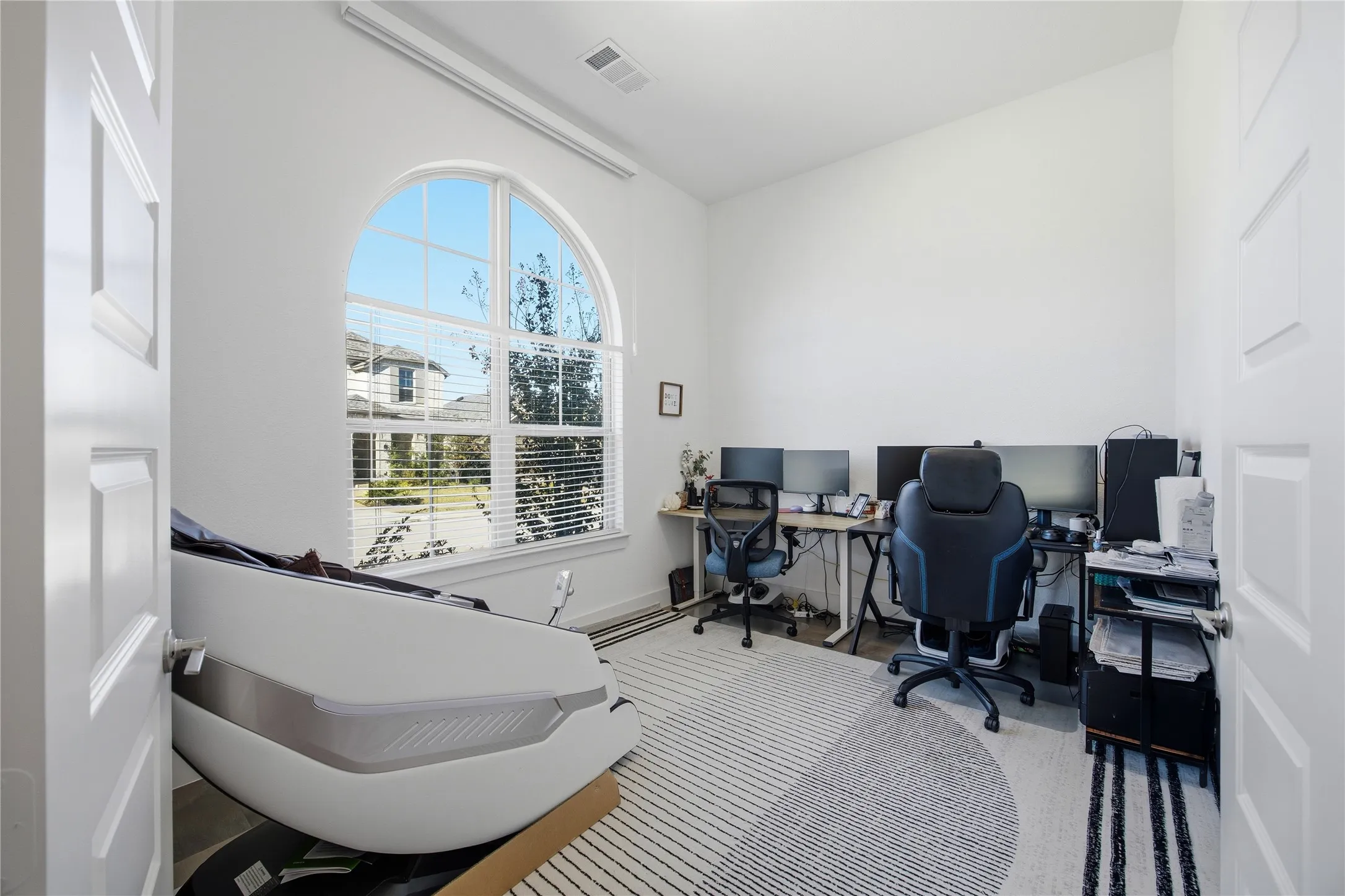 Arched window with gridded panes, high ceilings, and light wall finishes