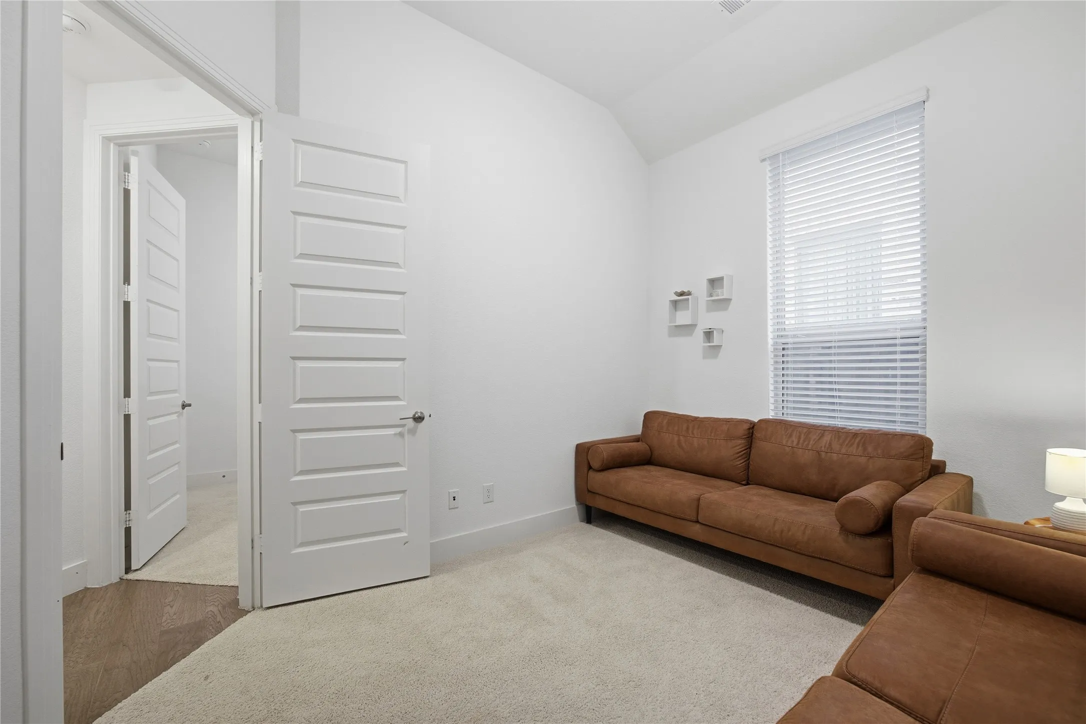Carpeted room with high ceilings, a window with blinds, and white paneled doors
