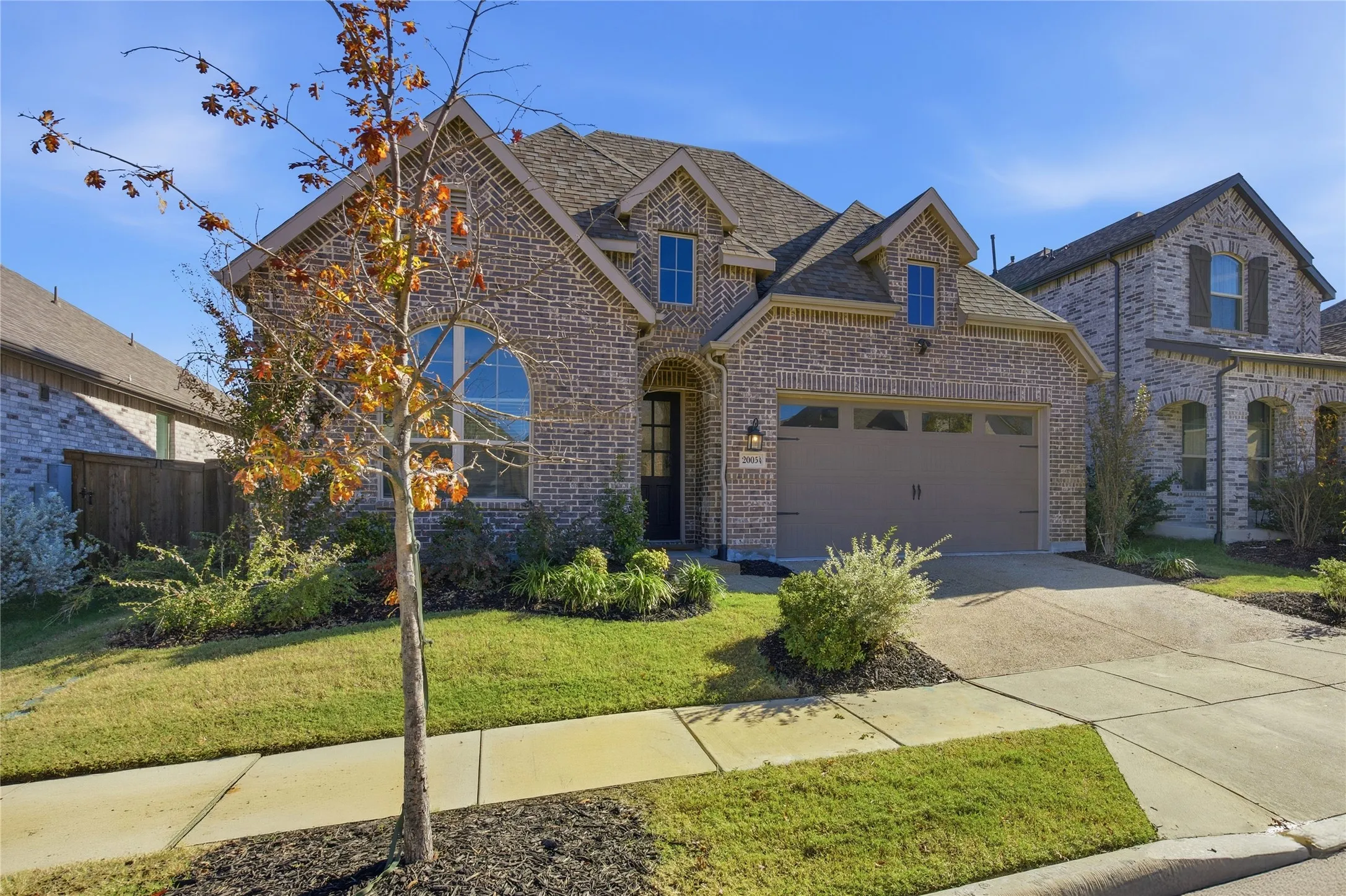 Brick exterior with a gabled roofline, arched window, and attached two-car garage