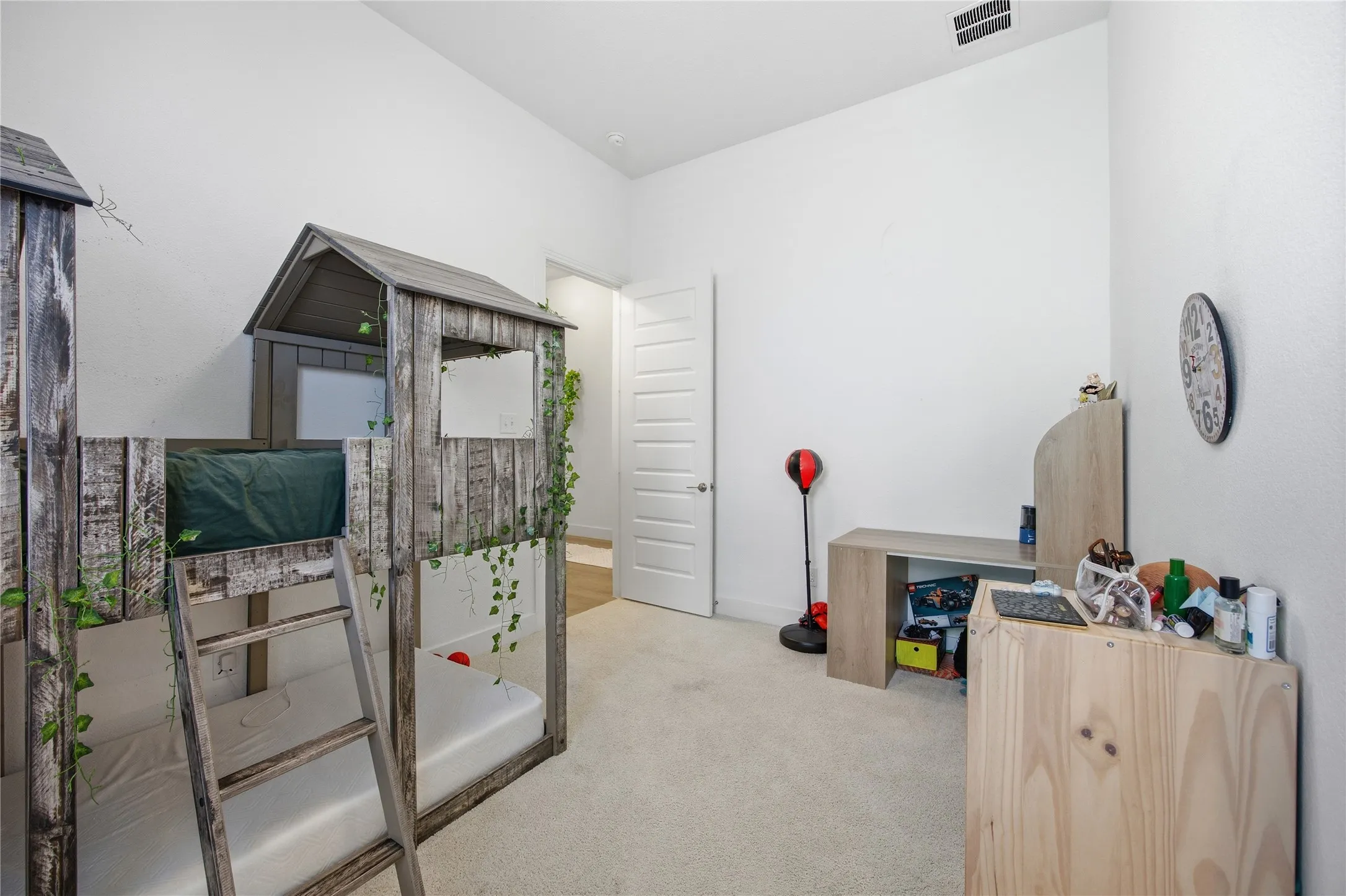 White walls, light-toned carpet flooring, and a solid white door with horizontal paneling