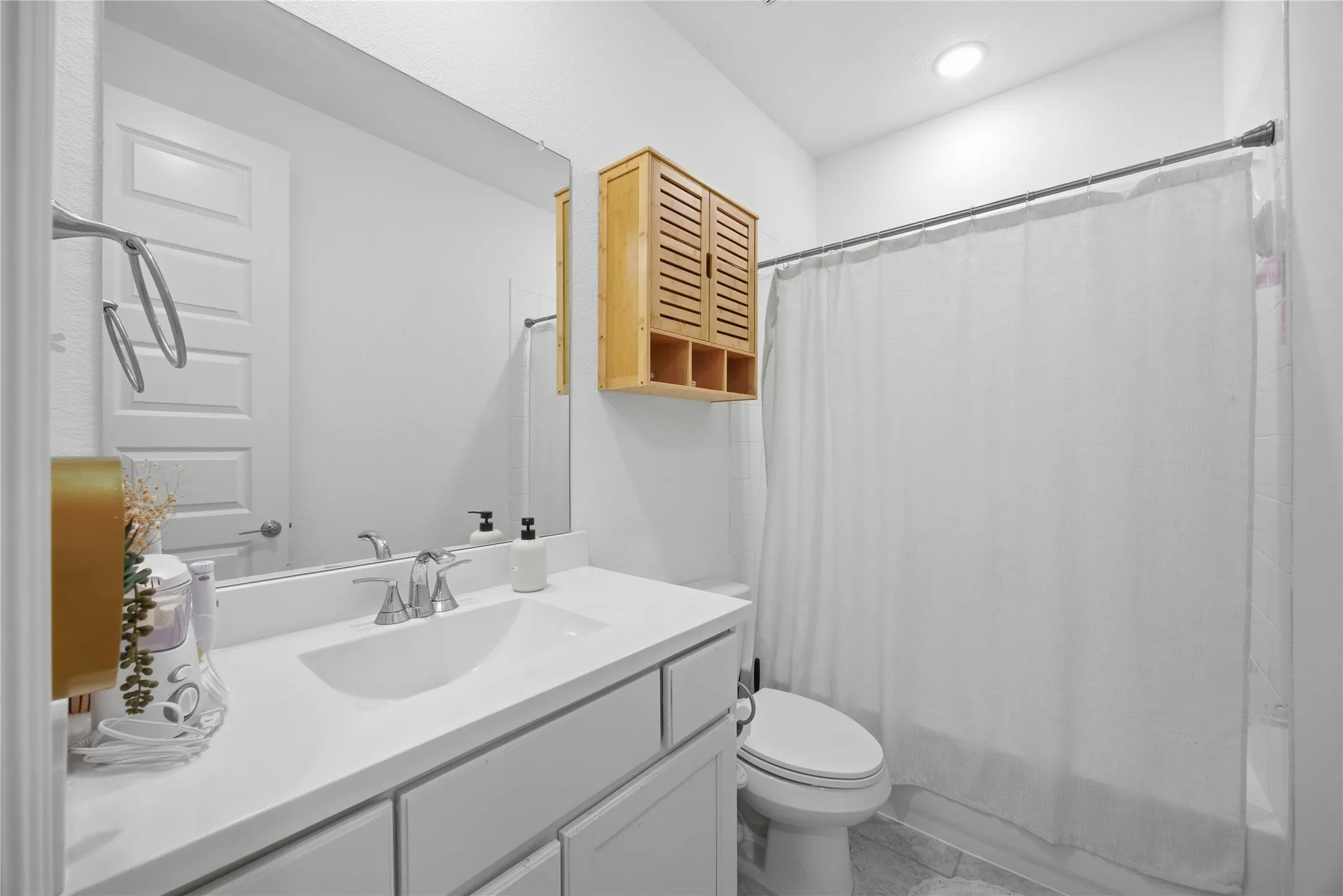 White vanity with integrated sink, chrome faucet, and expansive mirror