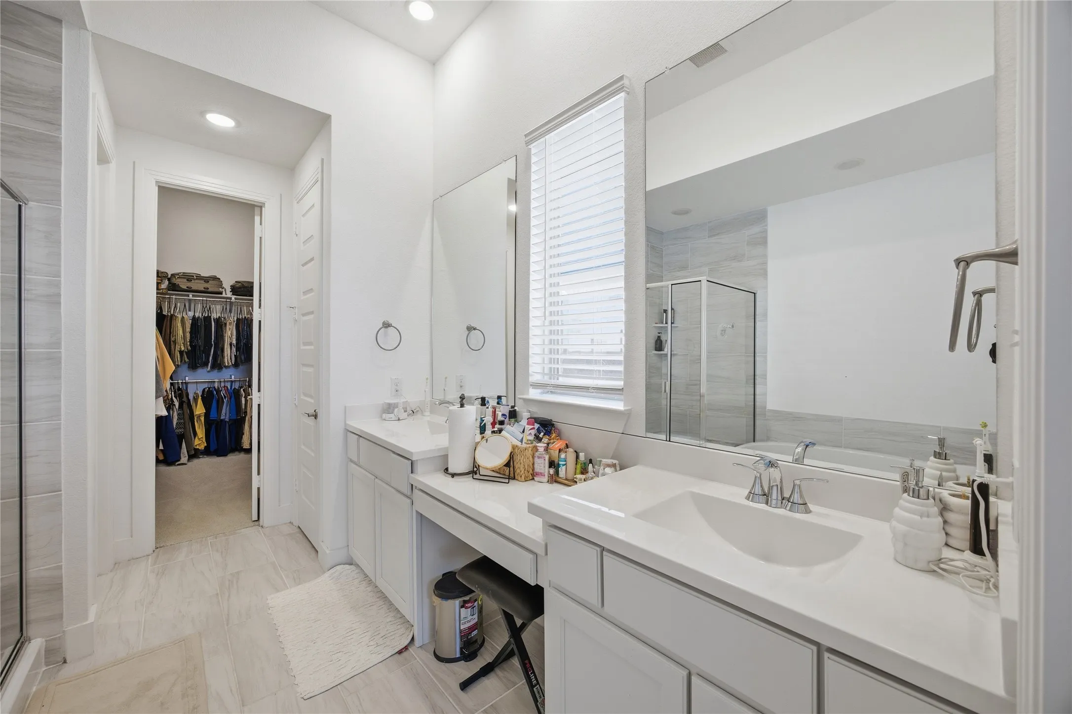 Built-in vanity with integrated sink, white cabinetry, a large frameless mirror, and recessed lighting