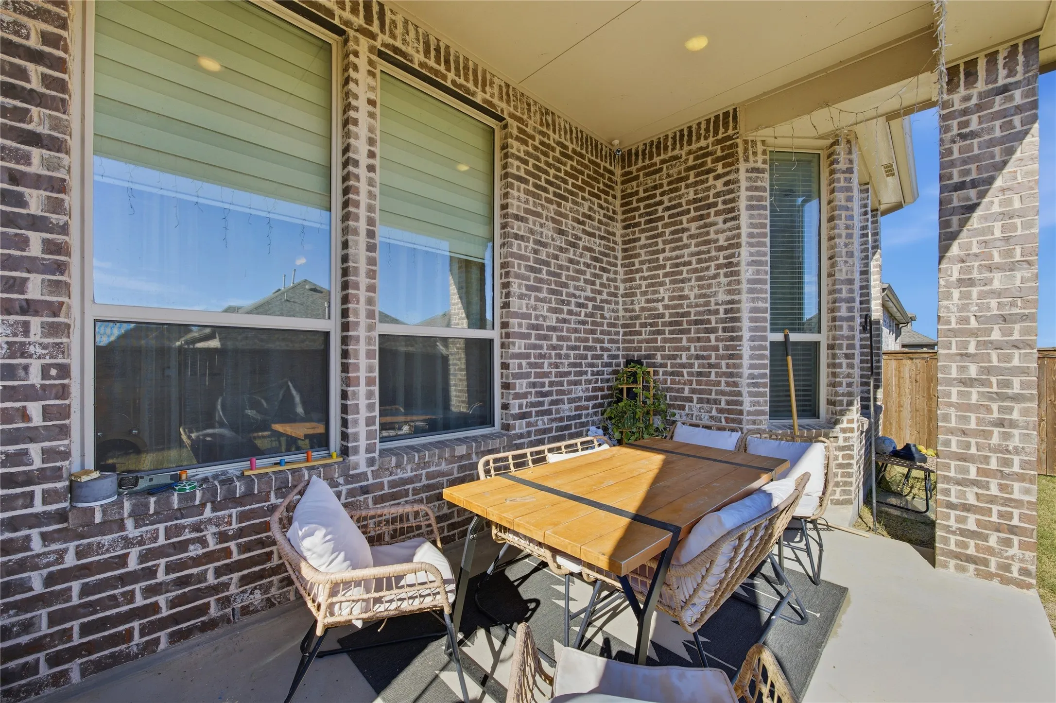 Covered outdoor patio featuring a brick exterior, recessed lighting, and a solid concrete floor