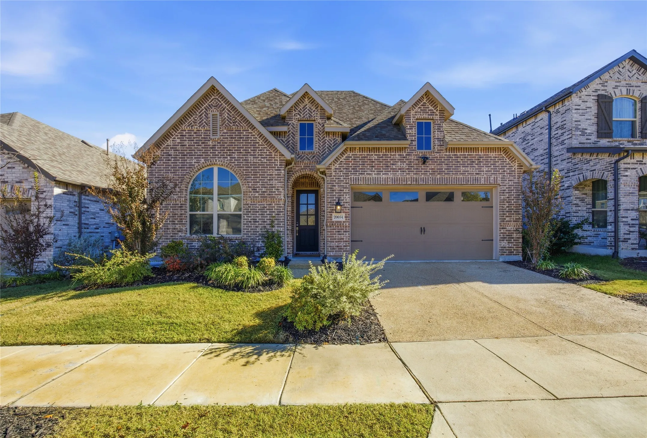 Brick exterior with stone accents, arched window, and a two-car garage