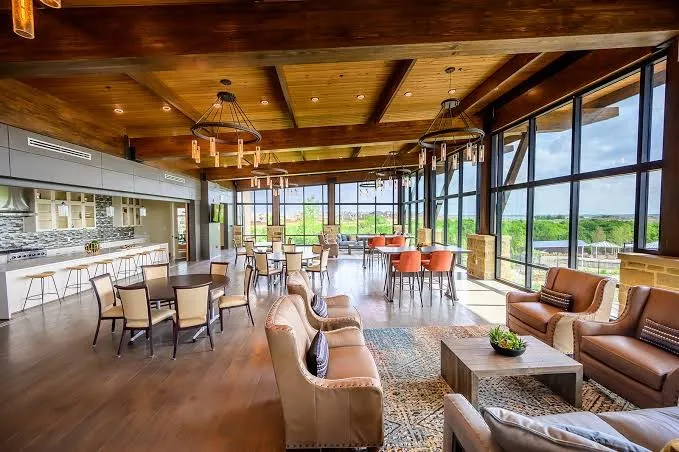 Expansive common area featuring a wood-finish ceiling with exposed beams, full-height windows, a built-in bar, and wood-finish flooring