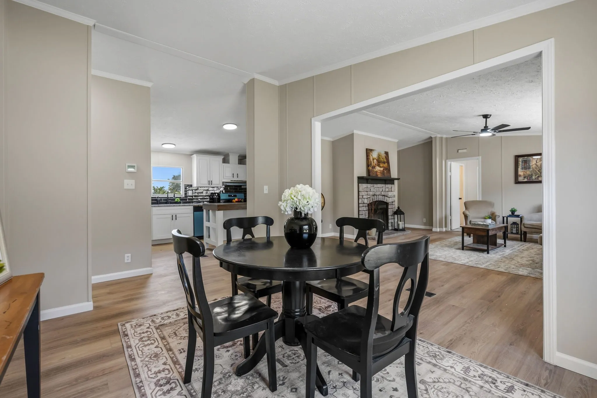 Elegant dining area showcasing a round black pedestal table, hardwood flooring, and neutral wall finishes