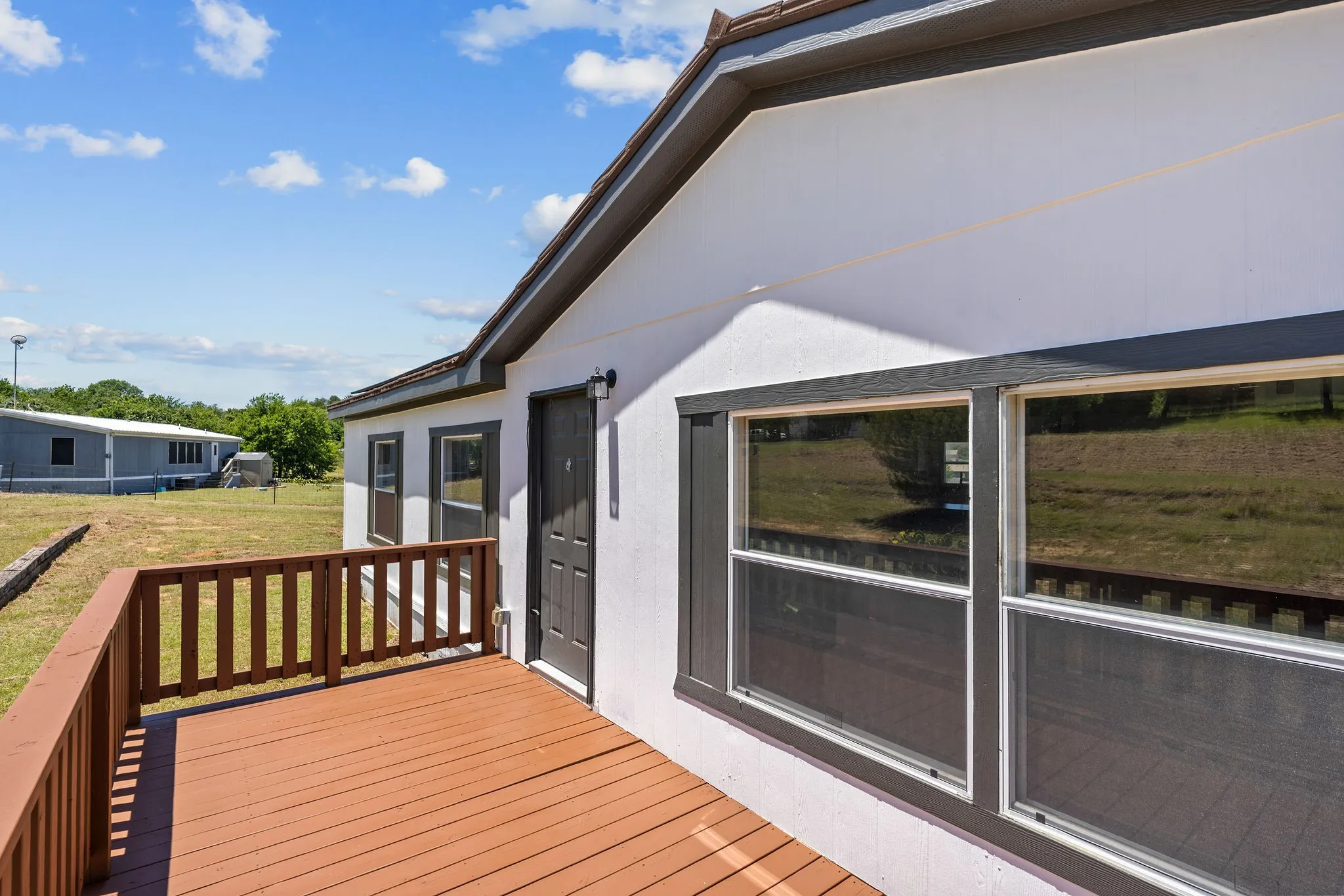 Exterior deck with wood railing, white stucco siding, and dark-framed windows