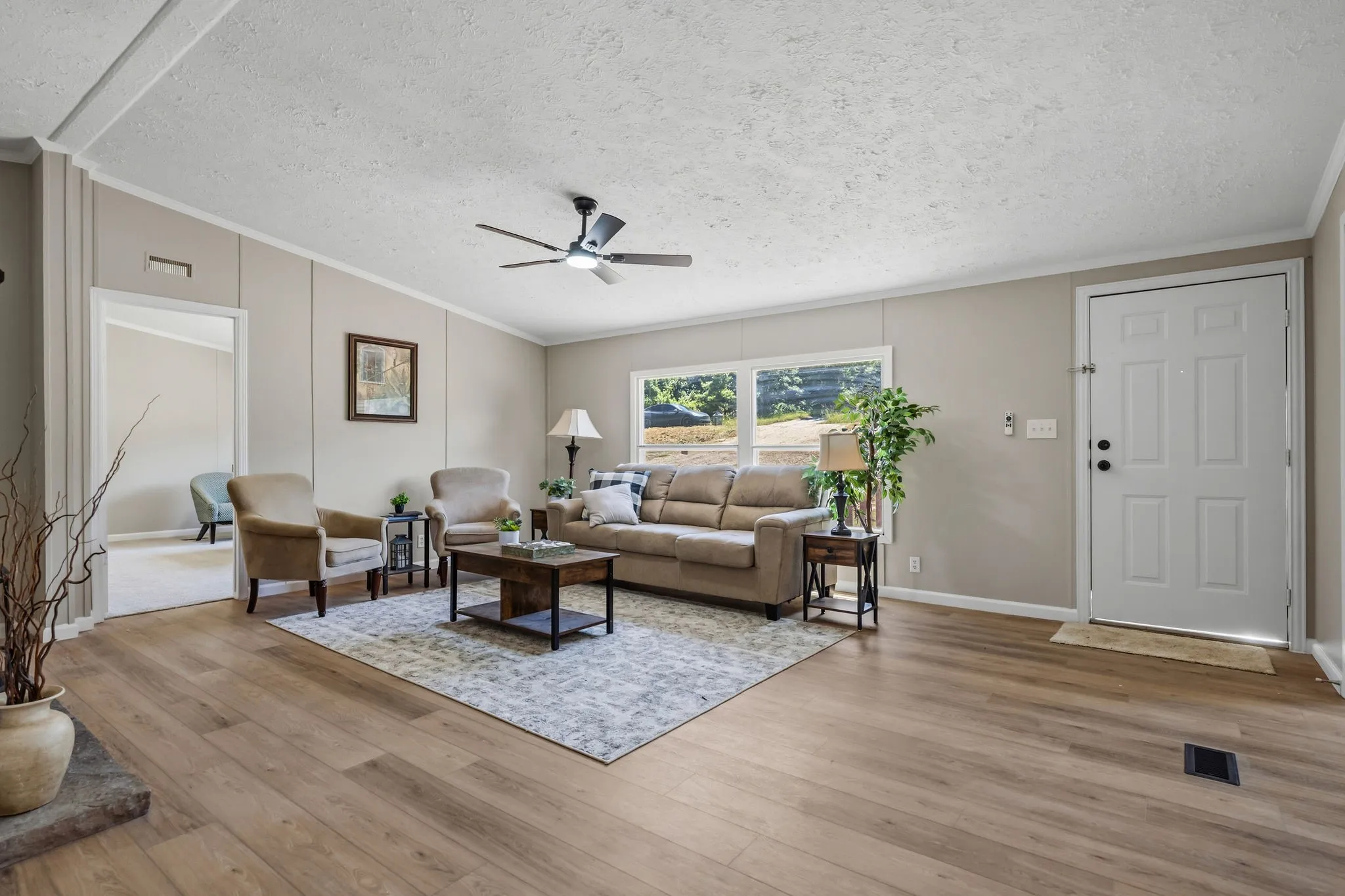Wood-finish flooring, neutral wall tones, white trim, a ceiling fan with integrated lighting, and multiple windows
