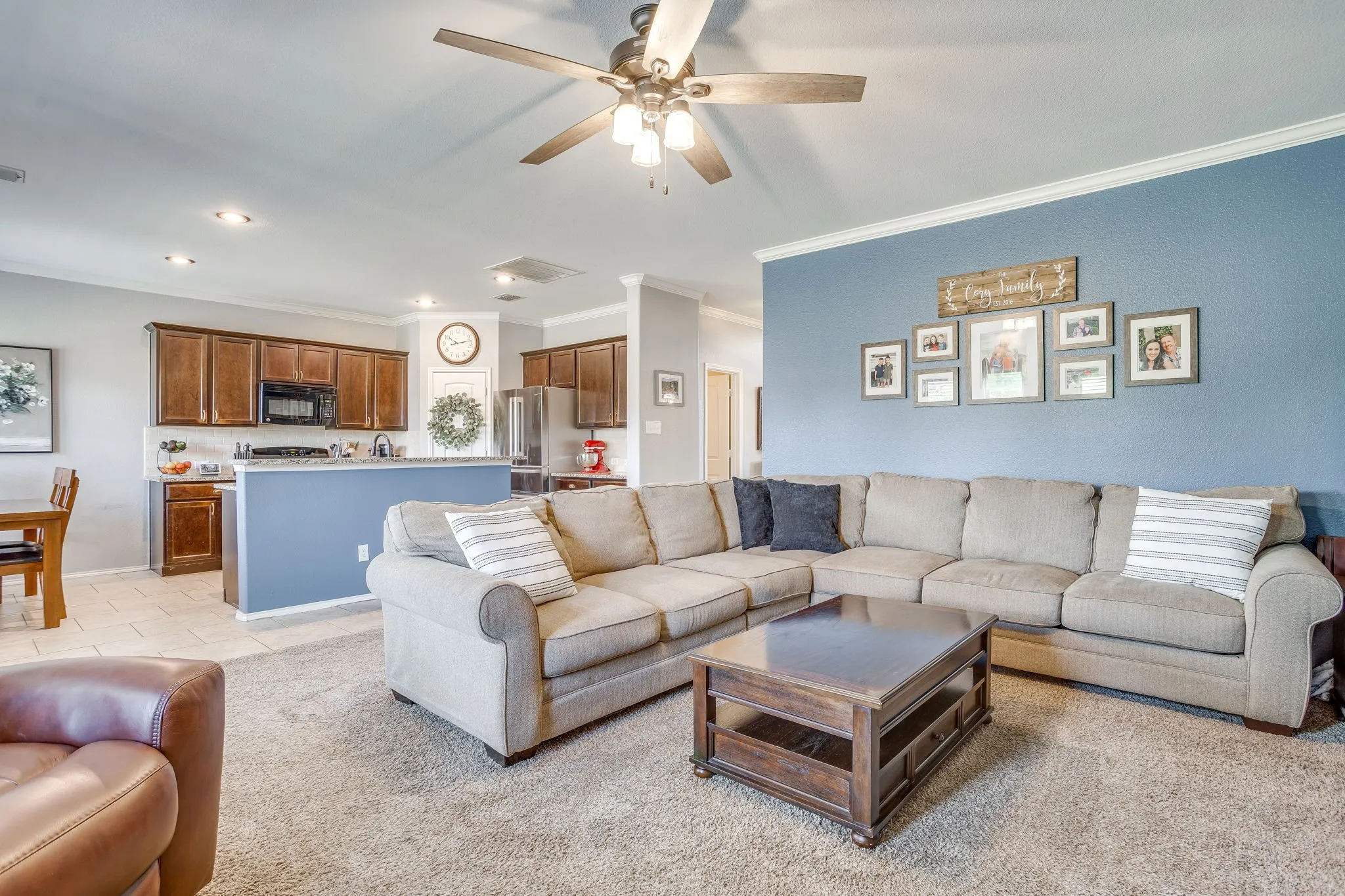 Spacious living area featuring a ceiling fan with integrated lighting, crown molding, and recessed lighting