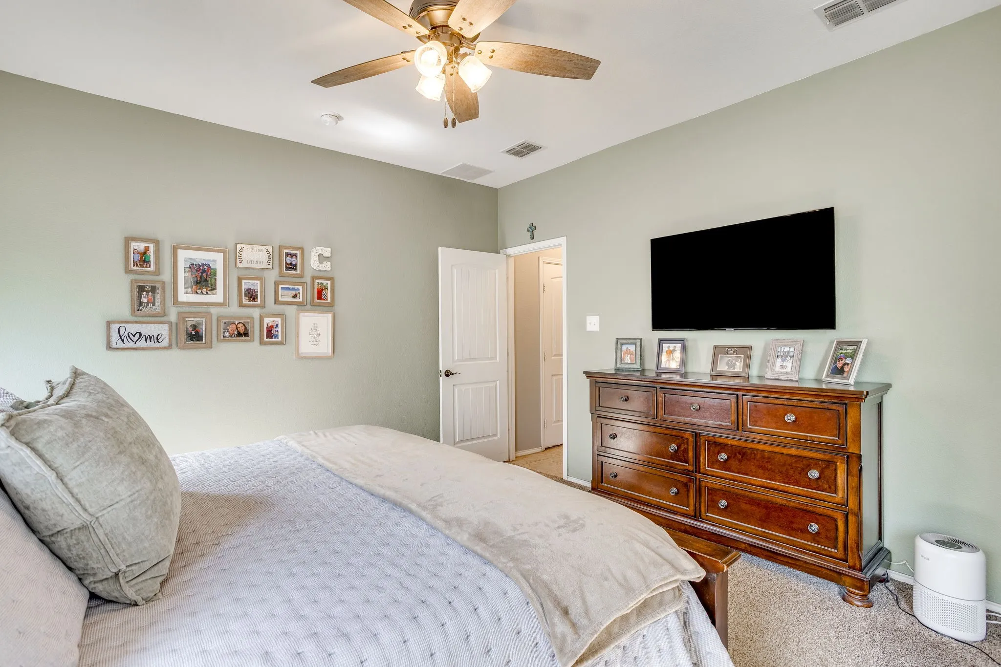 Ceiling fan with integrated lighting, neutral wall palette, carpeted flooring, and a paneled interior door