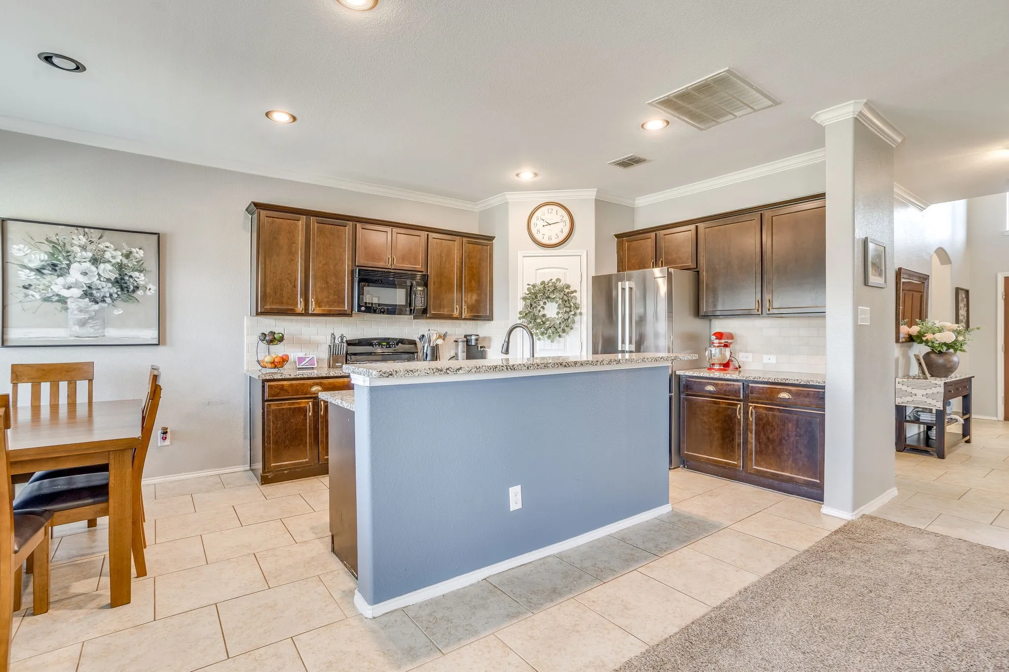 Kitchen featuring dark wood-finish cabinetry, granite countertops, stainless steel appliances, and a central island with a breakfast bar