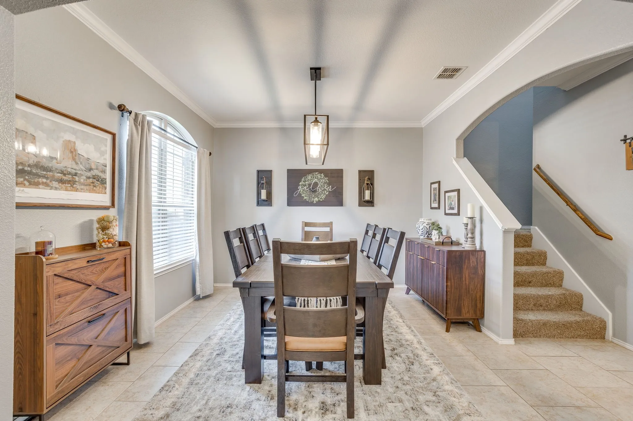 Spacious dining area featuring tile flooring, crown molding, an arched window, and a chandelier