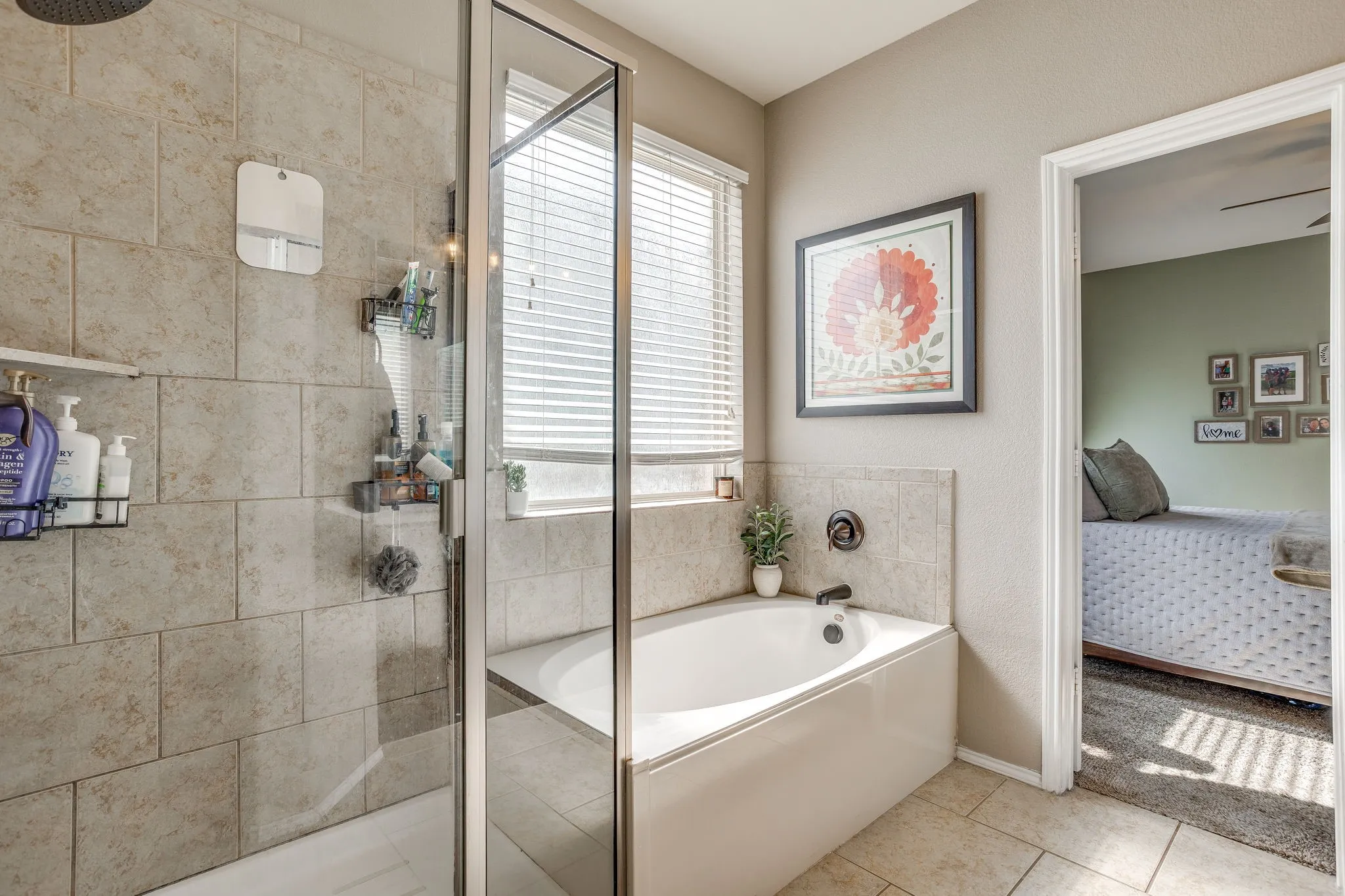 Bathtub with tile surround, glass-enclosed shower, and tiled flooring