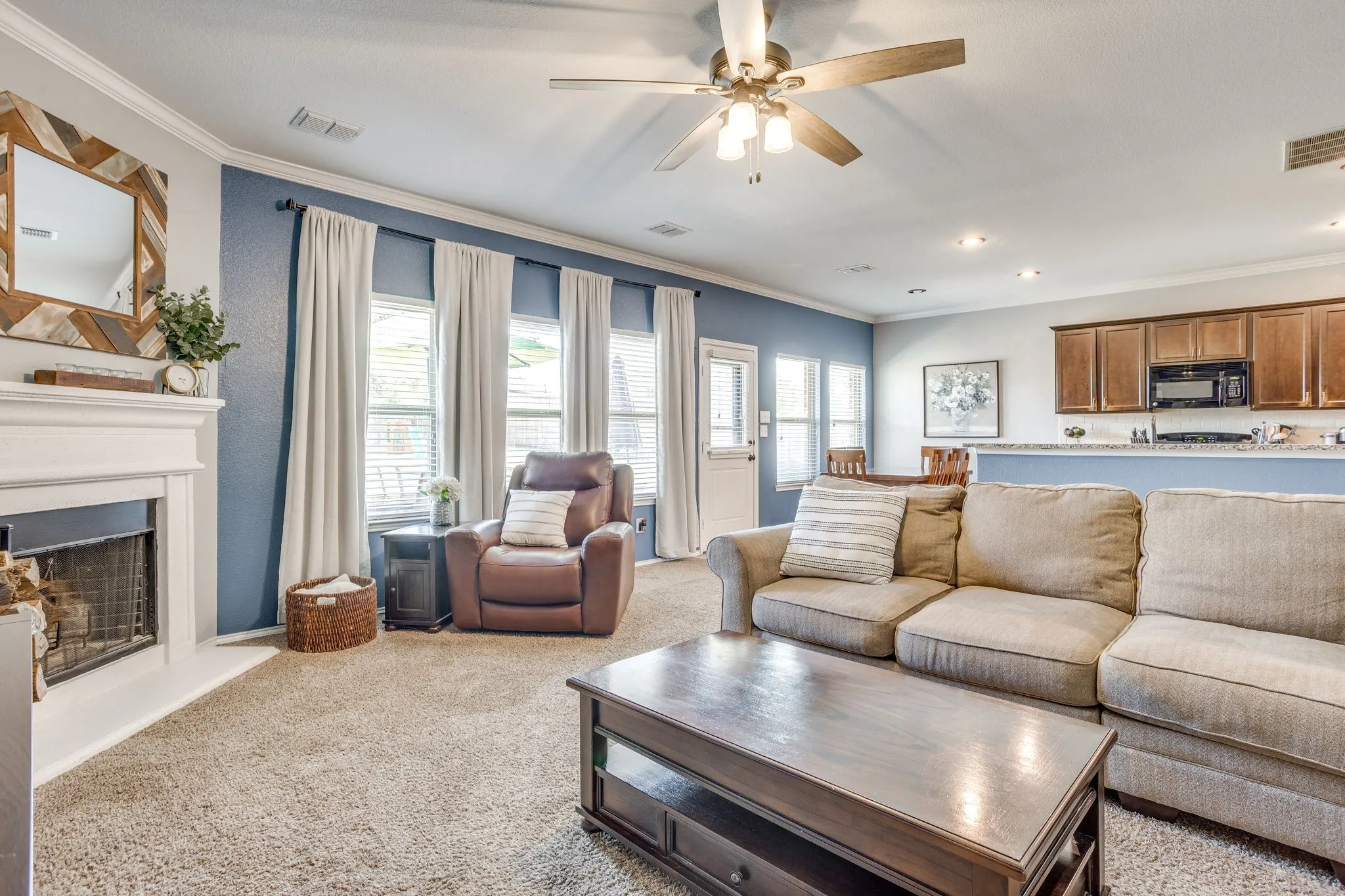 Living area with a decorative fireplace and white mantel, overhead ceiling fan, recessed lighting, and direct access to an outdoor area