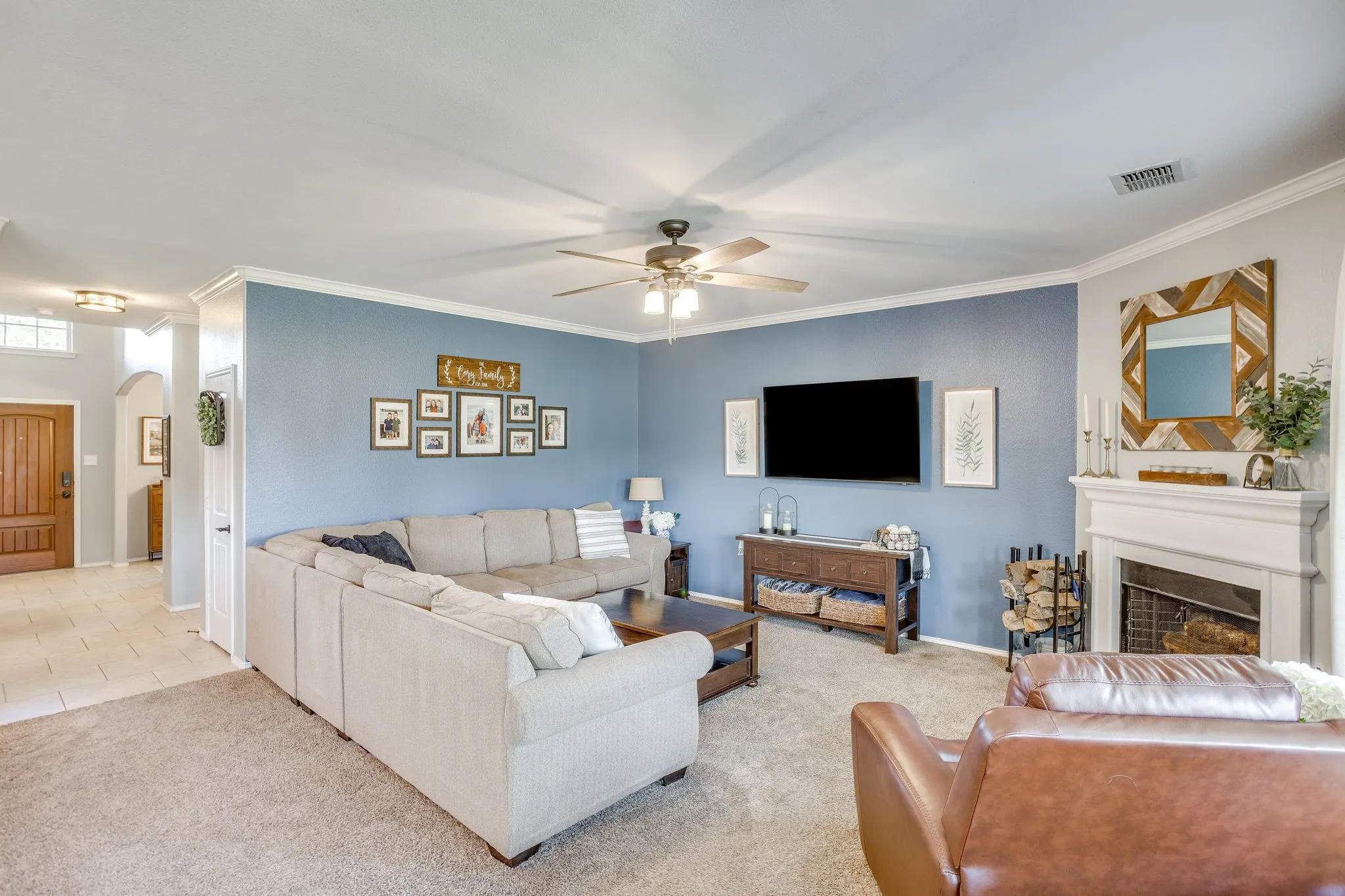Living area featuring a fireplace with a mantel, carpeted flooring, and a ceiling fan
