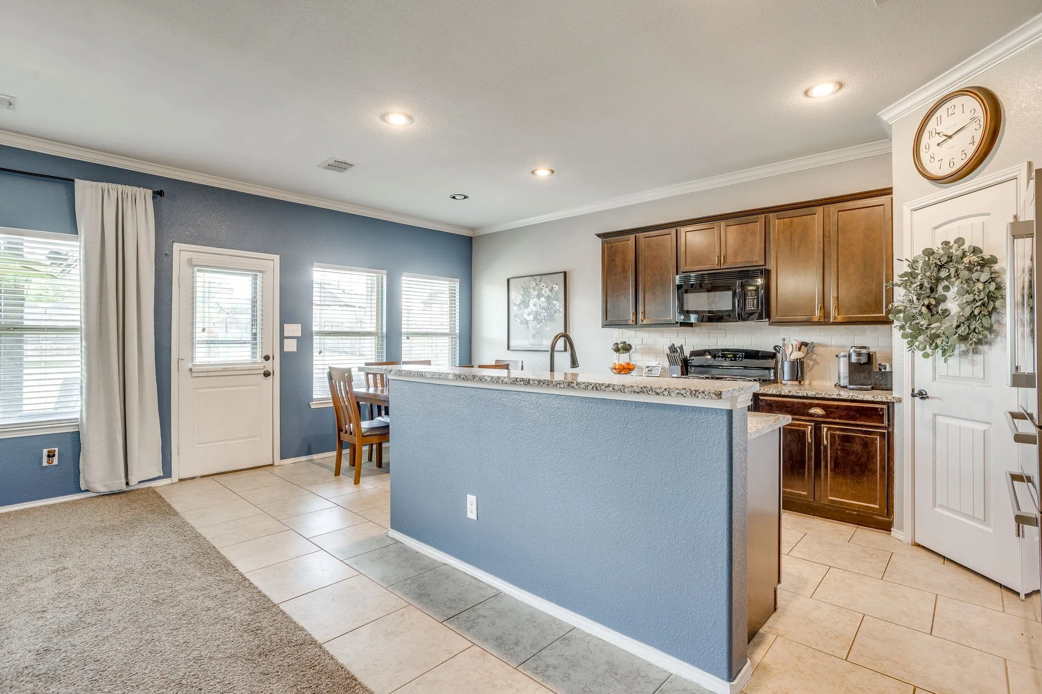 Kitchen featuring dark wood cabinetry, a built-in microwave, and tile flooring