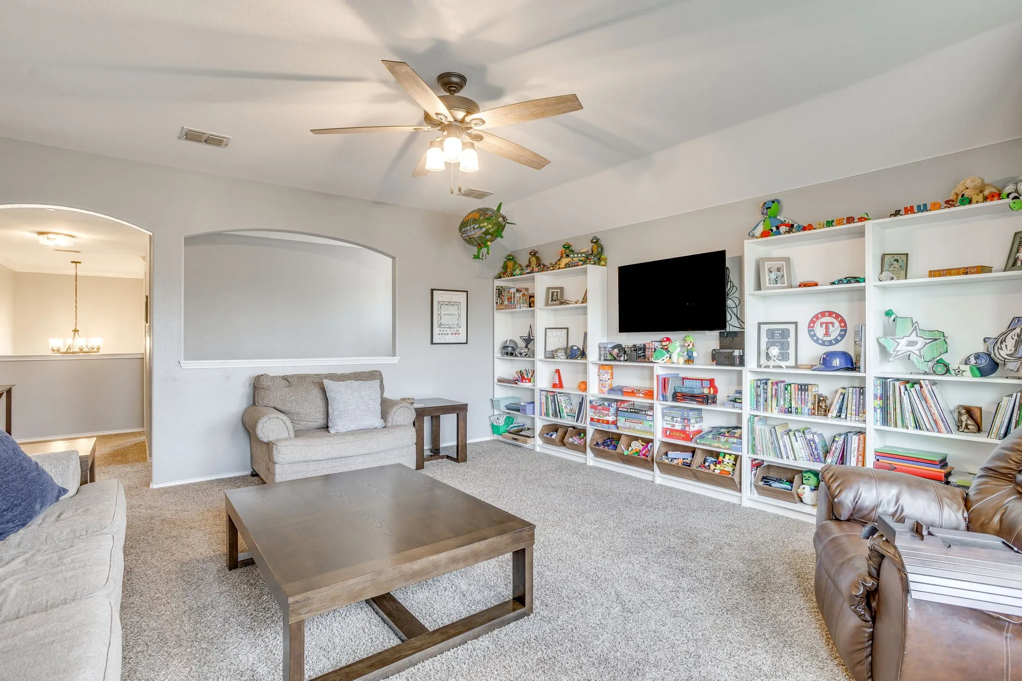Recessed ceiling fan with integrated lighting, built-in shelving, arched wall opening, and carpeted flooring
